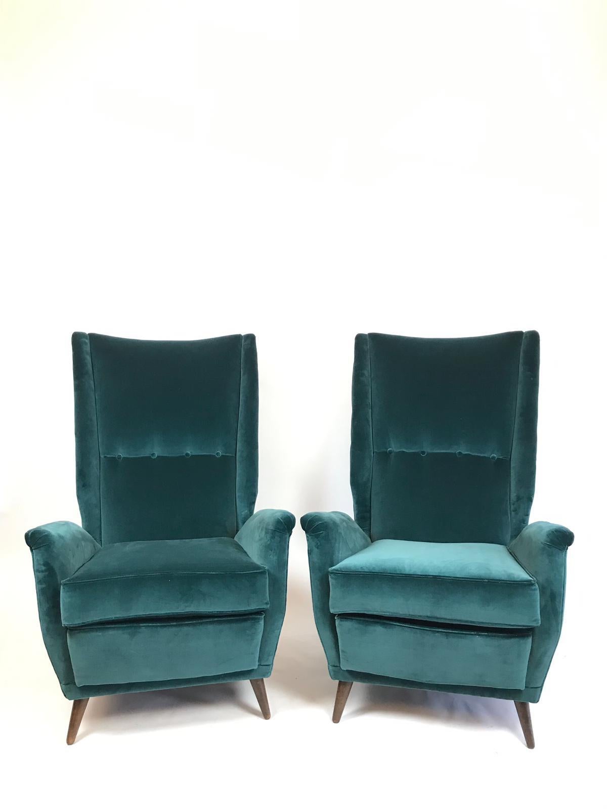 A magnificent and elegant pair of Gio Ponti newly upholstered high back armchairs in fine teal velvet.
The chairs are designed with beautiful lines with indented sides and buttoned backs standing on their original walnut feet. These armchairs can be