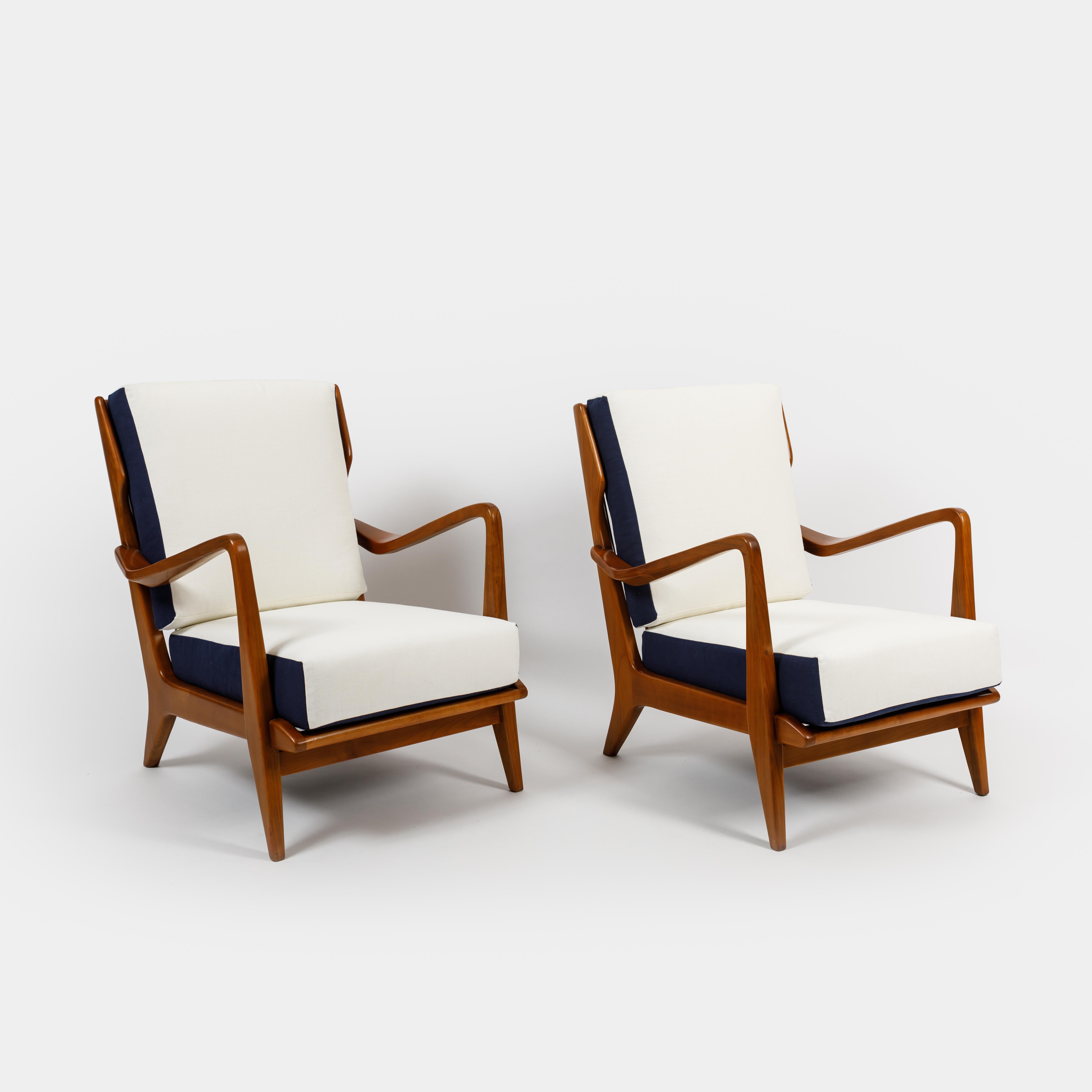 Designed by Gio Ponti and manufactured by Cassina model 516 pair of sculptural armchairs or lounge chairs, with white and navy cotton linen upholstered cushions on walnut frames, Italy, 1950s. Great architectural details in the frame including