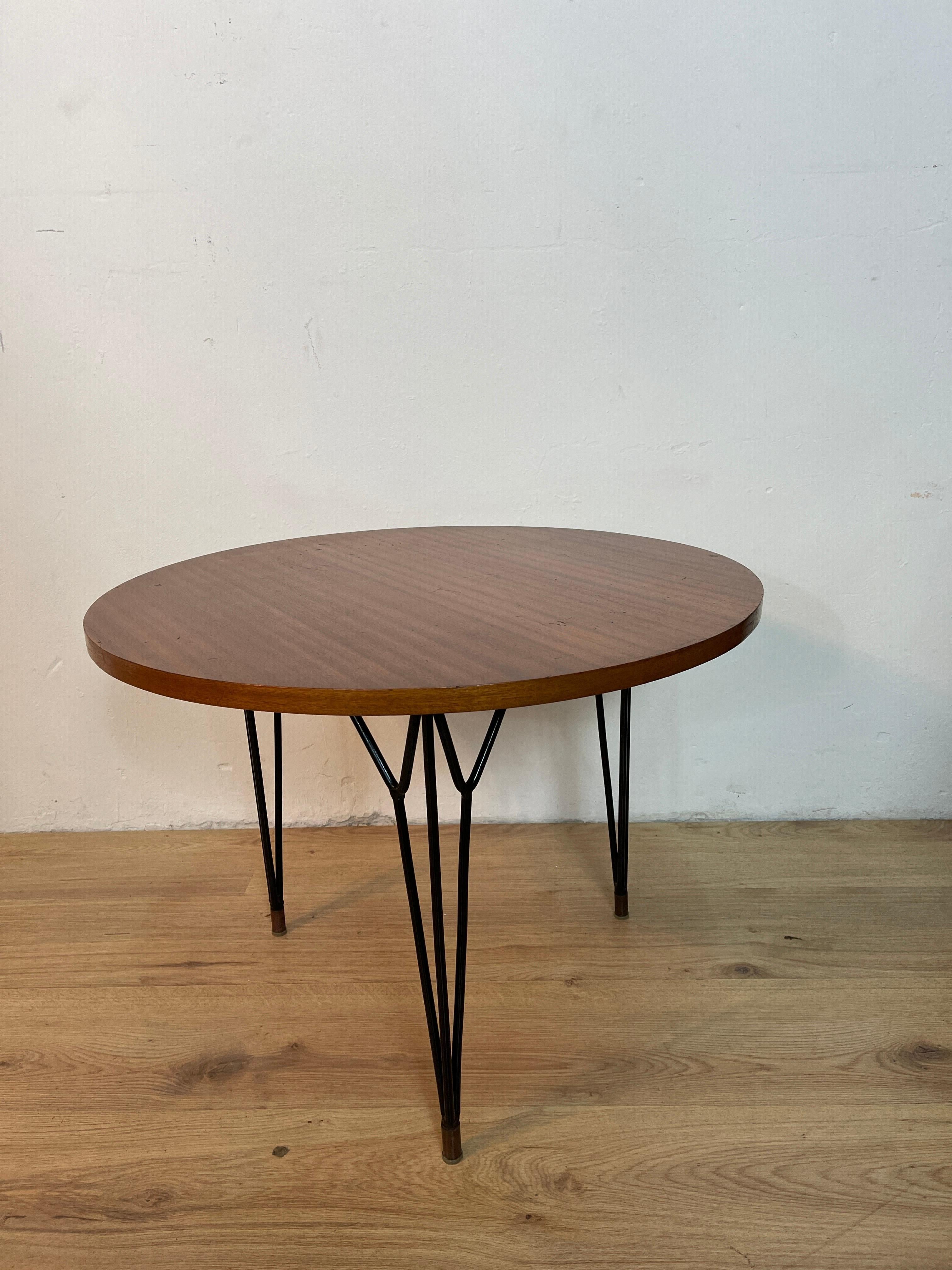 Round coffee table with 3 stylized black metal feet and wooden top, a design attributable to the work of the designer Giò Ponti.