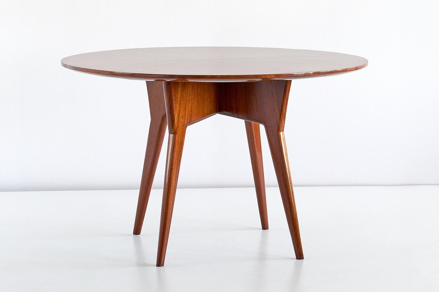 This round dining table was designed by Gio Ponti and manufactured in Italy in the early 1950s. The sculptural frame is executed in solid mahogany and consists of a cross base with 4 legs. The top is made of mahogany as well, with the upper layer