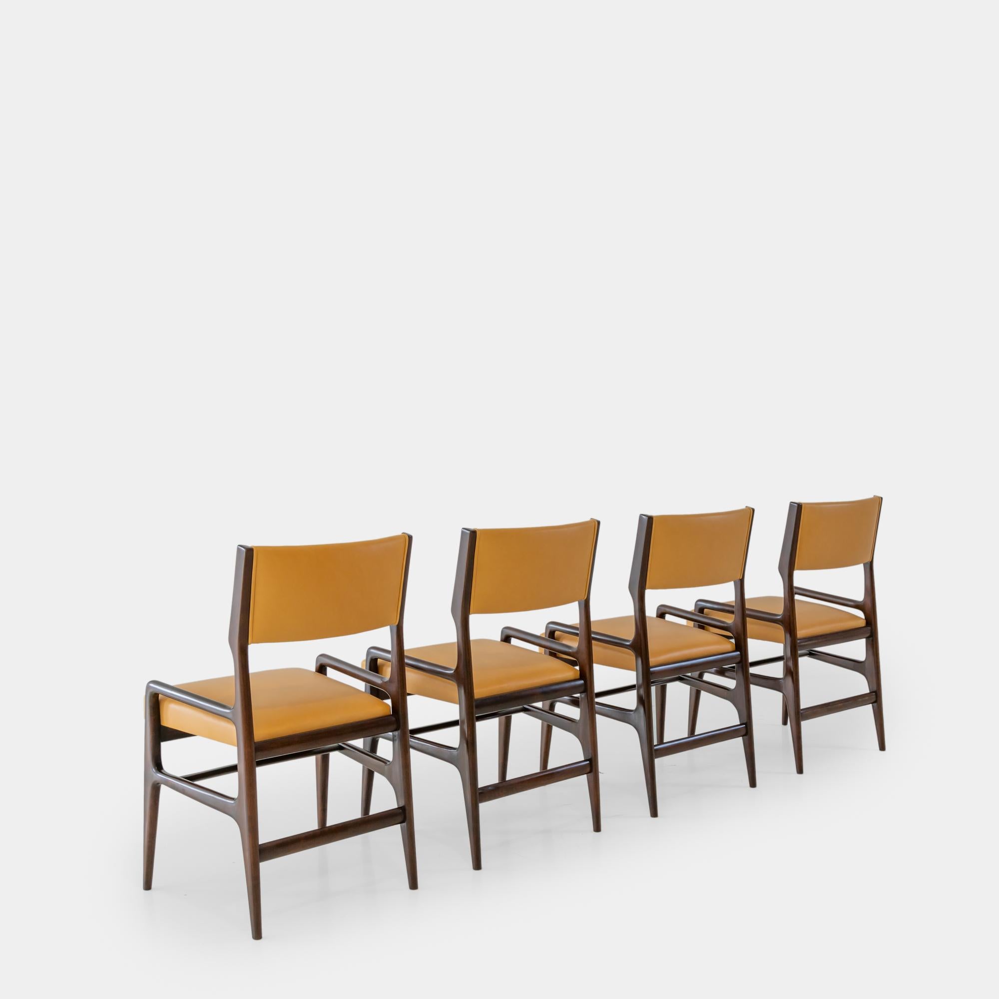 Designed by Gio Ponti and manufactured by Cassina for Altamira, New York, a very rare set of four dining chairs model AP 1676, circa 1953. These beautifully sculptural chairs have architectural walnut frames and are newly upholstered in a sumptuous