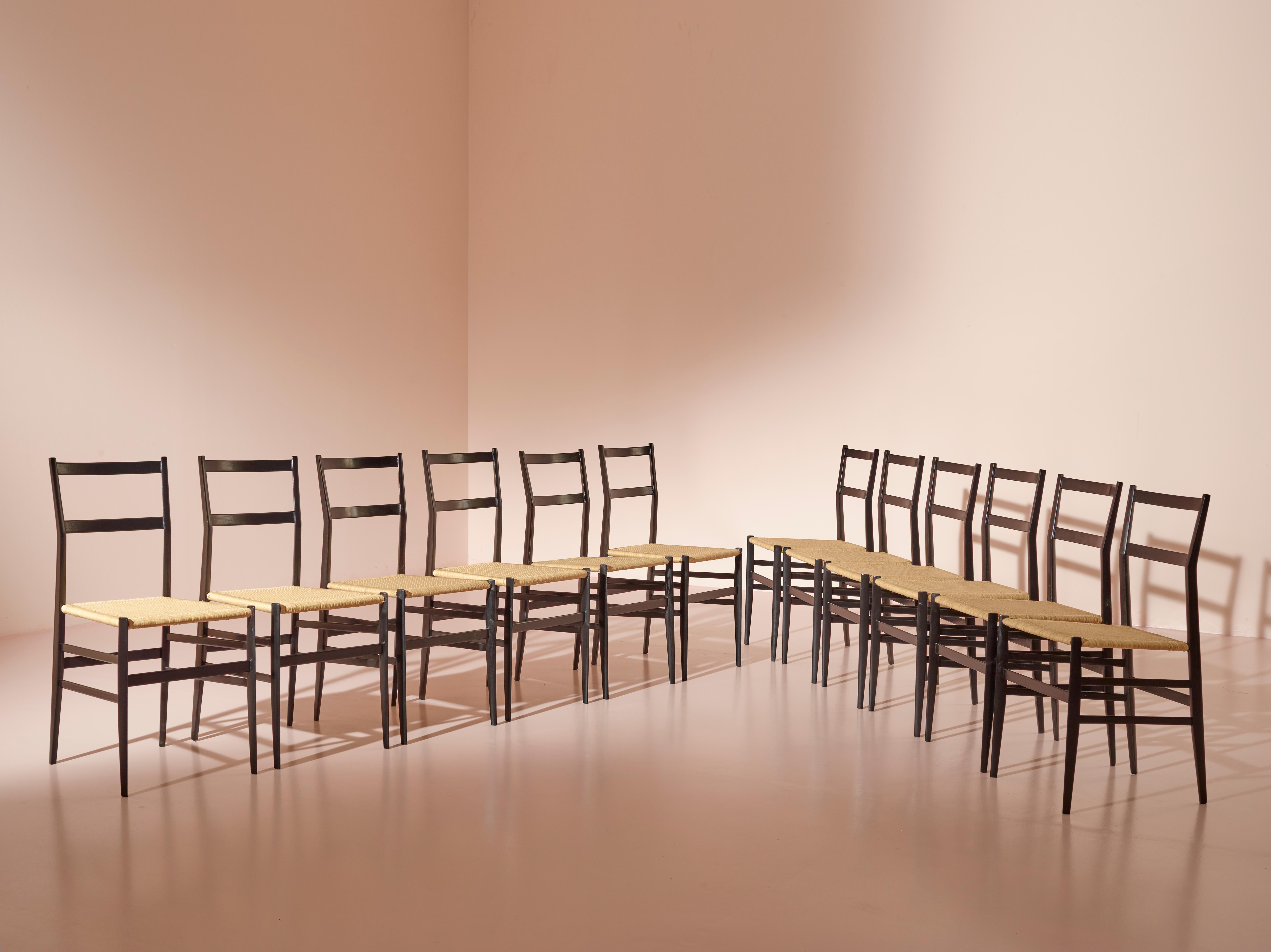 Ein Satz von zwölf Superleggera-Stühlen, sorgfältig restauriert in schwarzer Anilinfarbe. Die ursprünglichen geflochtenen Strohsitze wurden durch neue, sorgfältig gearbeitete Sitze ersetzt, die das leichte Wesen des Stuhls bewahren. 

Der