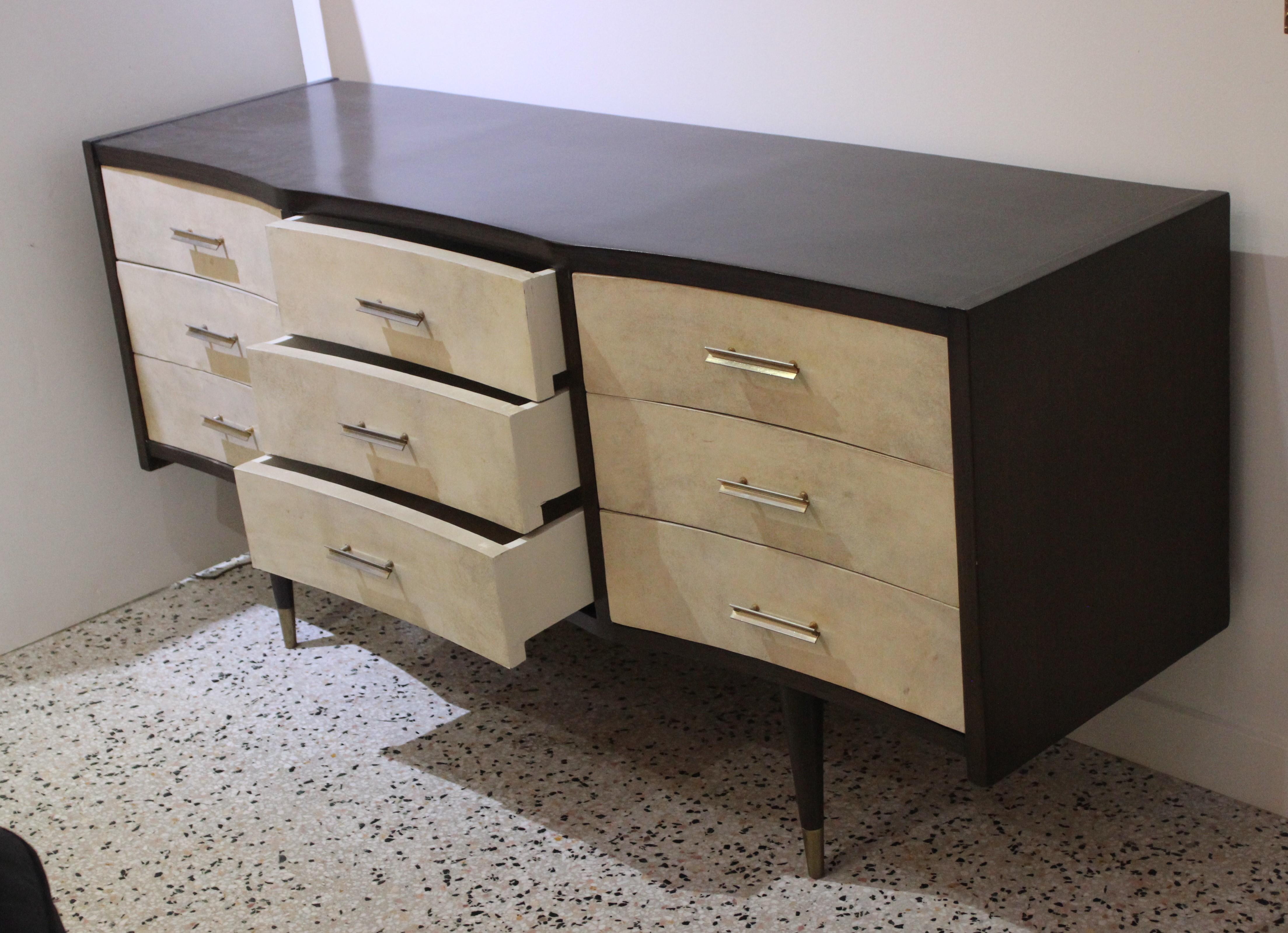 This stylish chest of drawers is very much in the style of pieces created by Gio Ponti in the mid-20th century. The piece has been professional restored as of June 2020. The concave drawer fronts are covered in a light colored beige parchment