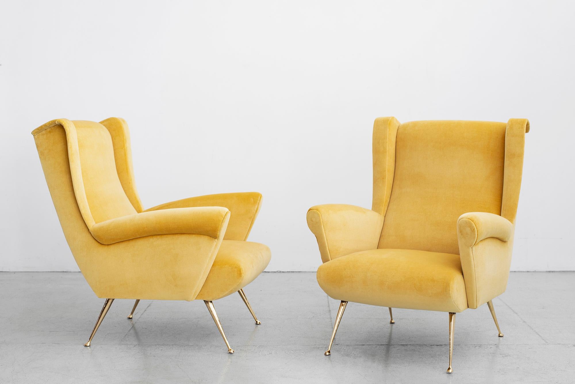 Italian pair of club chairs in the style of Gio Ponti with wingback arm and angular shape.
Brass legs - reupholstered in beautiful lemon yellow velvet.
Polished brass tapered legs.
 