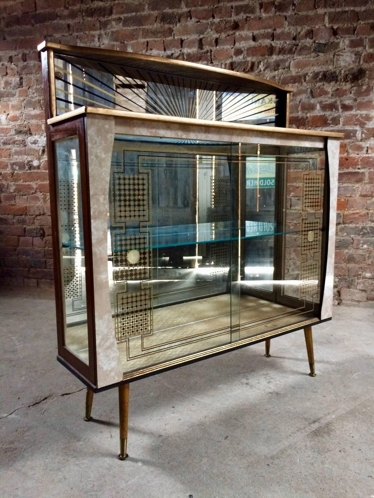 A magnificent and truly stunning midcentury Italian display cabinet in the manner of Gio Ponti circa 1950s, fabulous mirrored top with sunburst etching above two sliding glass doors both depicting gold pattern design, internally there is one glass