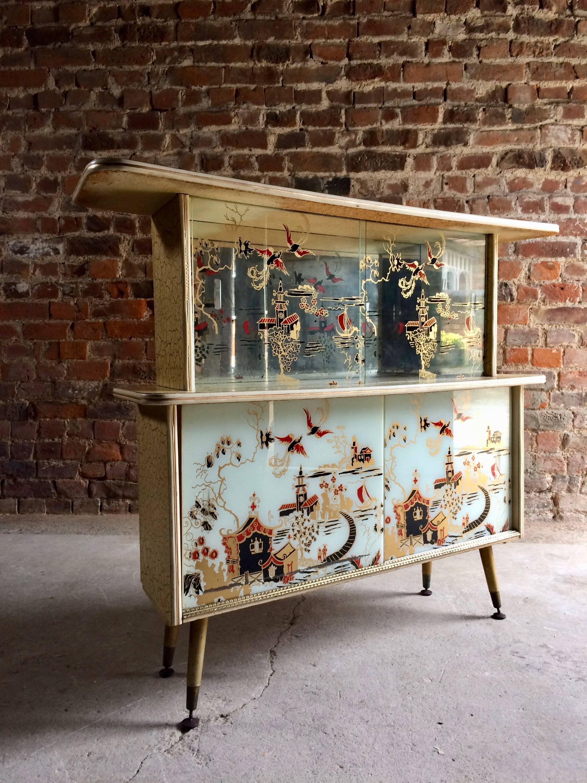 A magnificent midcentury Italian display cabinet in the manner of Gio Ponti circa 1950s, fabulous Pagoda style design, two sliding glass doors both depicting gold Chinese designs over two opaline glass doors featuring Pagodas, mountains, flowers and