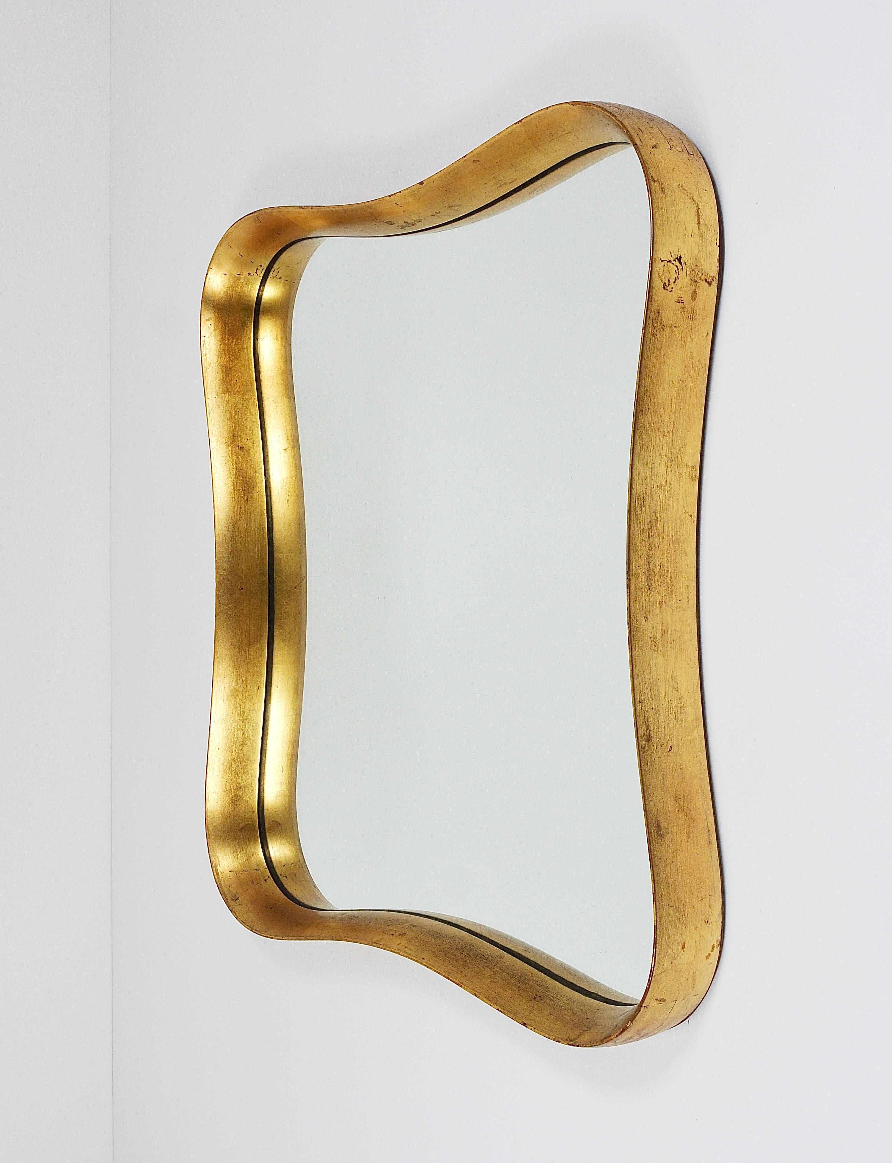 A wonderful Austrian modernist wall mirror with a lovely curved gold-plated lime wood frame from the 1940s. Manufactured by Max Welz Vienna, Austria. In very good condition with charming patina on the gold leaf finish. In the style of Gio Ponti.

