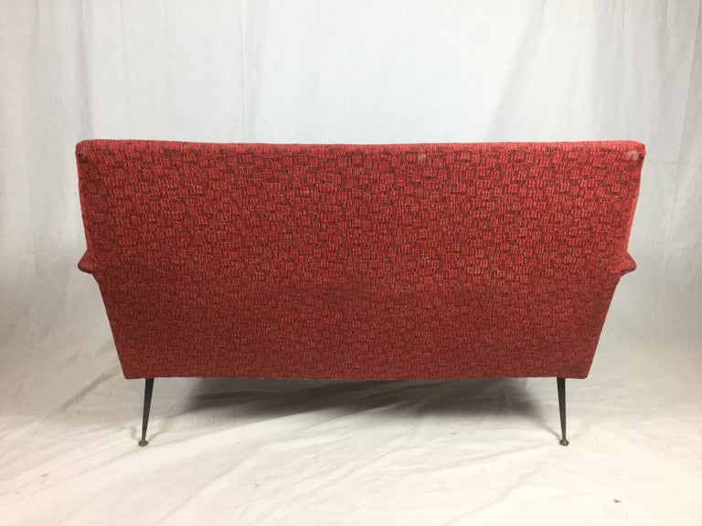 A red two-seat sofa in the style of Giò Ponti, manufactured in Italy in 1960s. The sofa features the original red fabric upholstery and typical 'stiletto' supports.
 