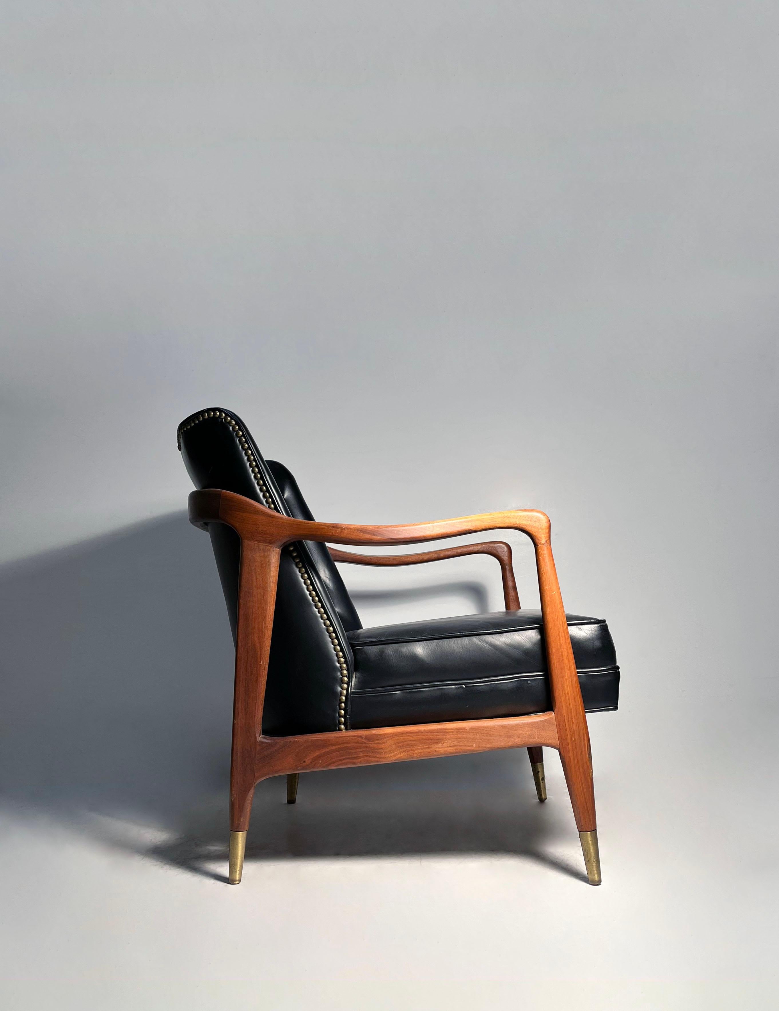 Chaise longue en noyer sculpté vintage de style Gio Ponti.
Sabots en laiton.
Cuir noir d'origine. 

Nous avons un modèle assorti qui est d'une couleur rouge tendre. Je crois qu'elle est en vinyle, contrairement à cette chaise noire. Veuillez