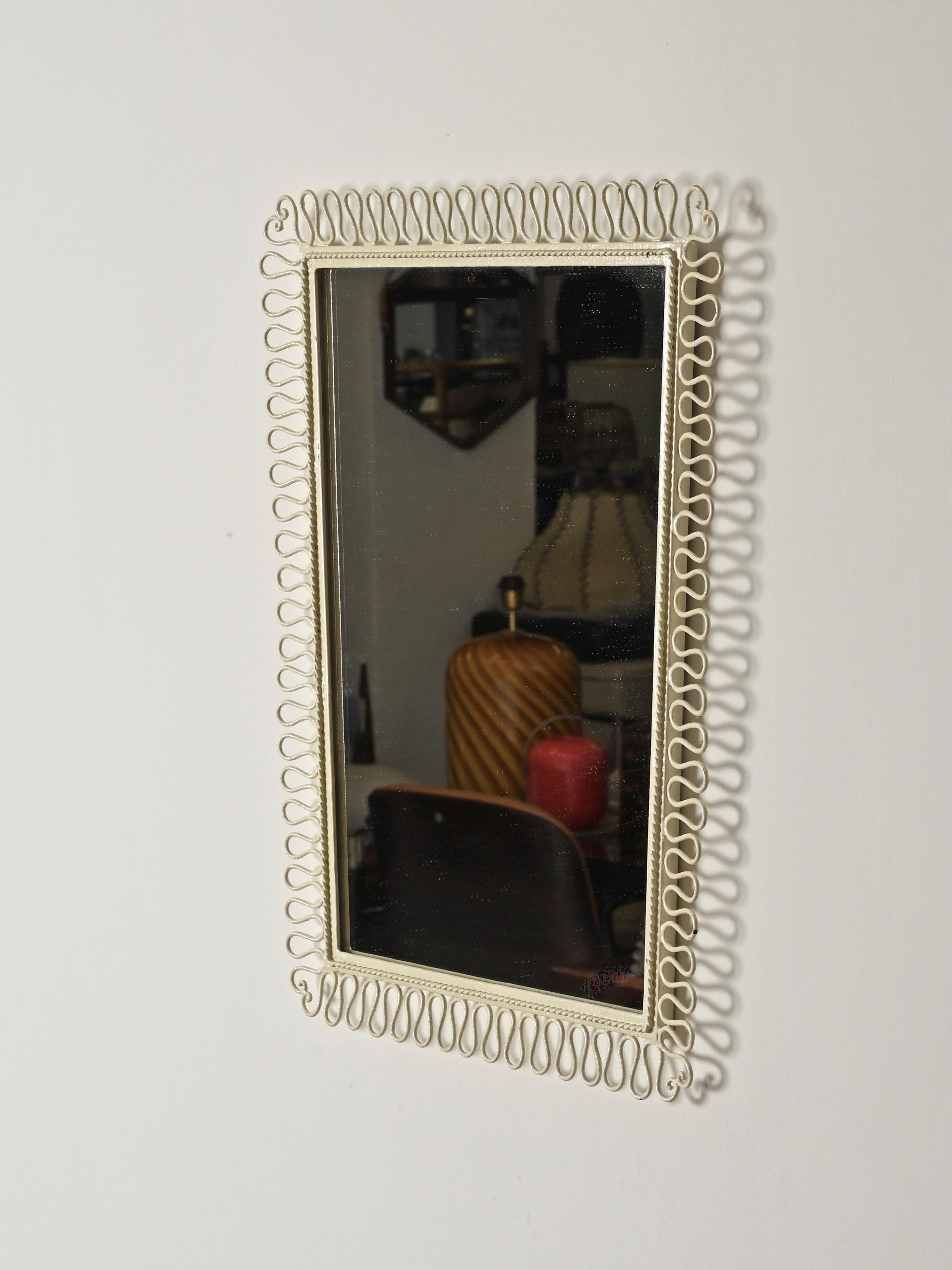 Stunning wall mirror in wrought iron, enameled in ivory white. This incredibly elegant and unique mirror was produced in Italy during the 1950s, clearly designed in the style of Gio Ponti.

In fabulous condition, the frame features a stylish looped