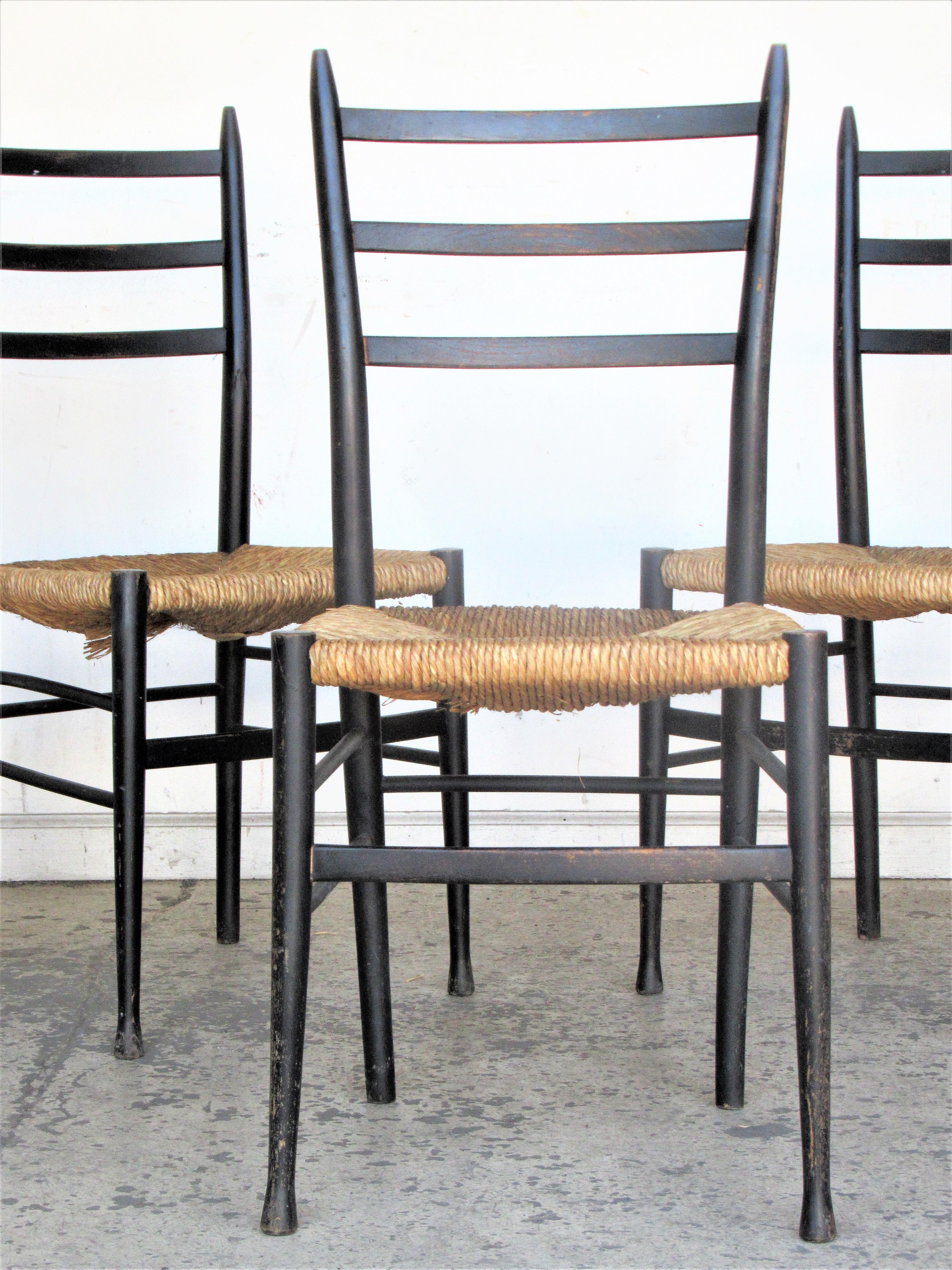 A set of three Gio Ponti Superleggera Chiavari style side / dining chairs with the original woven rush seats and ebonized lacquered surface. One chair with paper label on underside - Made in Italy and instructions for cleaning rush seats. Circa