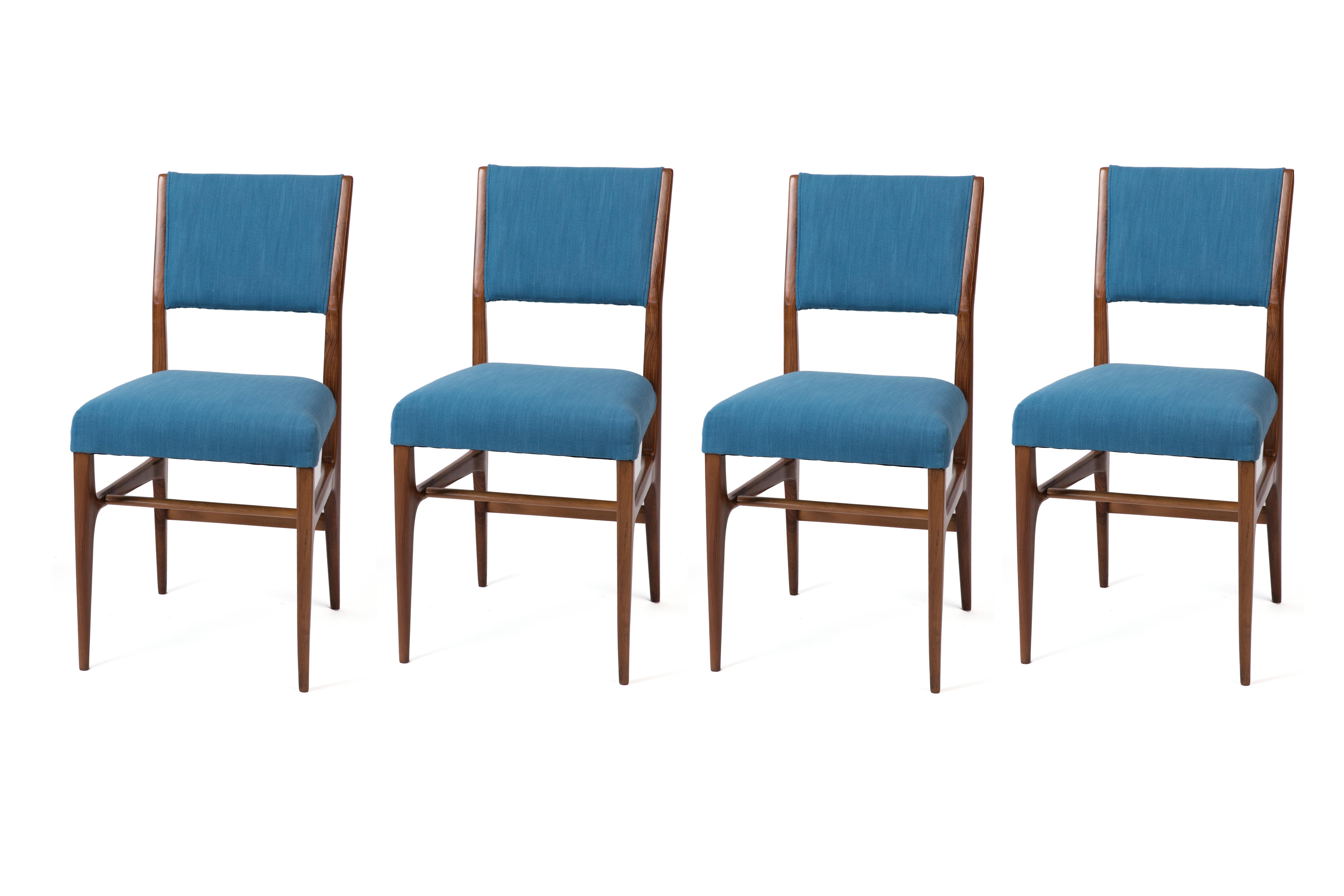 Set of four walnut dining chairs designed by Gio Ponti and manufactured by Cassina for Singer & Sons in the 1950s. Newly refinished and upholstered in a bright, velvety blue jewel tone. Price listed is for the set of 4.