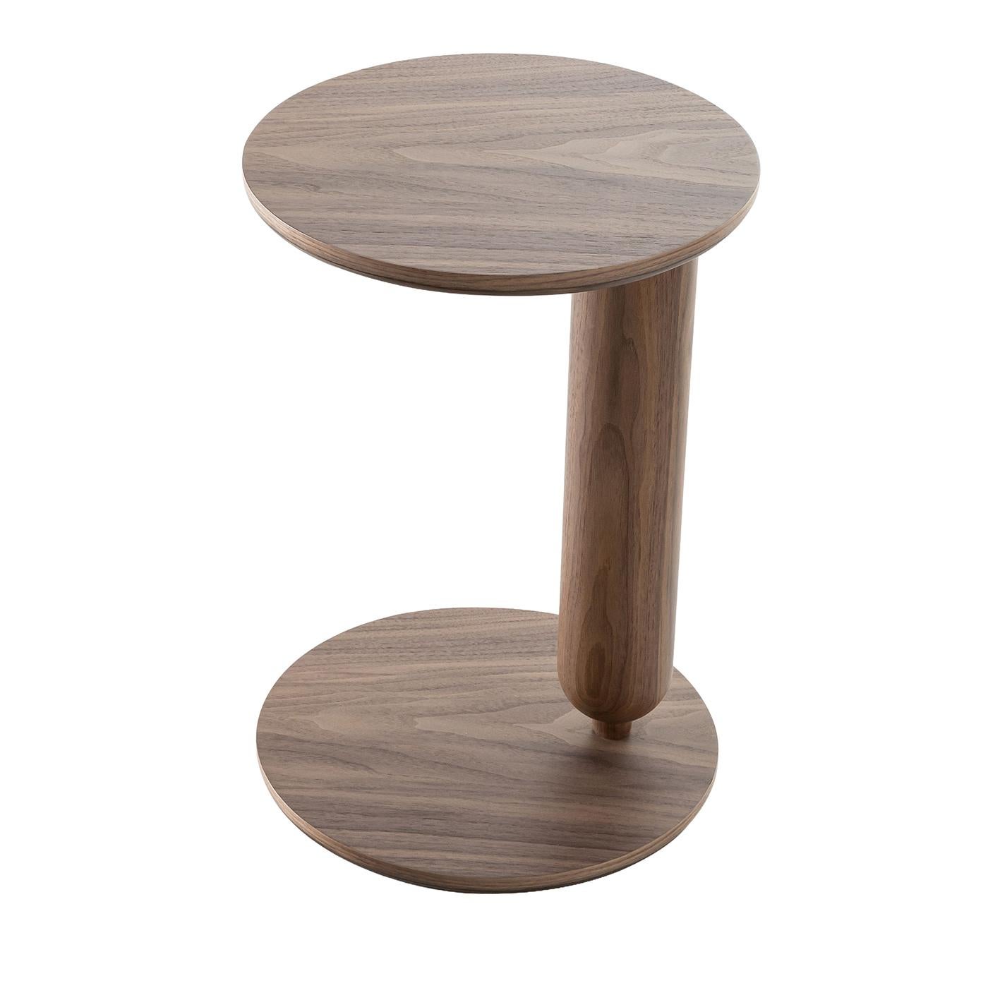 Side table featuring a distinctive asymmetrical design with a gently rounded top and matching base connected by a cylindrical support. Crafted from solid walnut canaletto, the table showcases refined natural wood grain and a smooth finish. Available