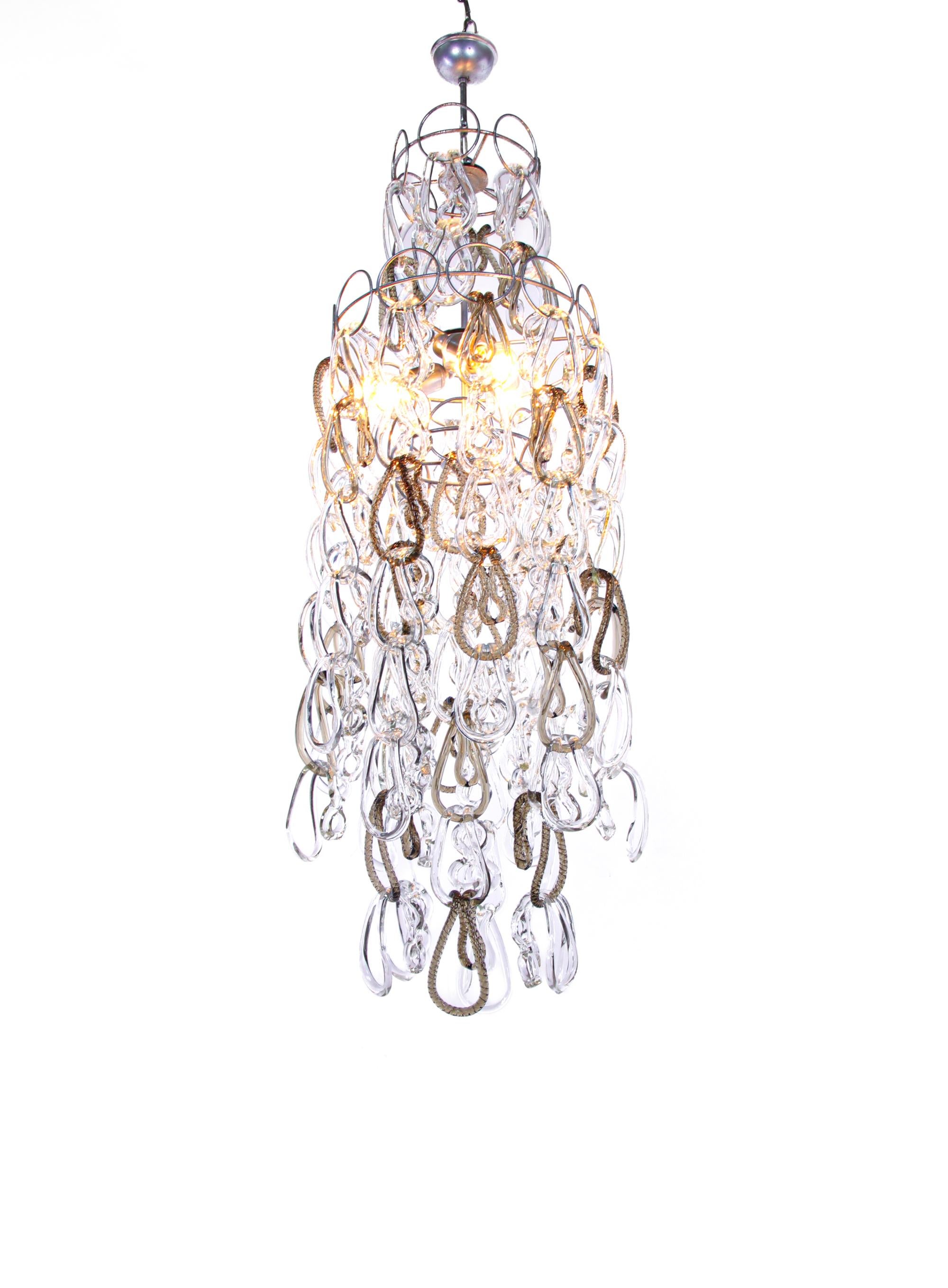 Imposant lustre cascade Giogali avec de nombreux verres de Murano transparents et ambrés entrelacés sur une armature métallique. Les 90 verres clairs et les 25 verres ambrés de Murano peuvent être disposés individuellement, ce qui permet d'adapter