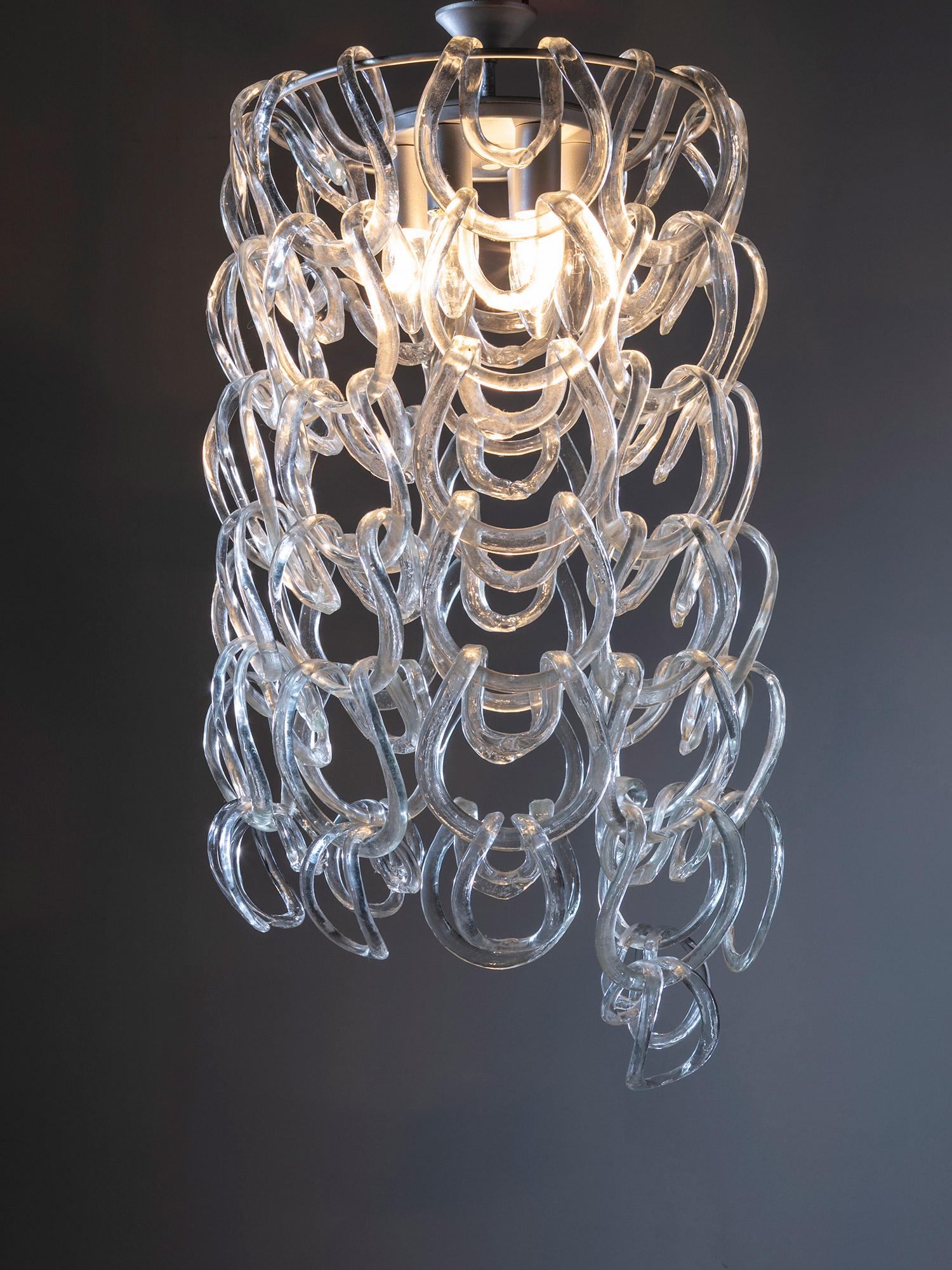 Giogali-Kronleuchter von Angelo Mangiarotti für Vistosi, Murano.
Der runde Metallrahmen ermöglicht es, die Glasbänder miteinander zu verbinden, wodurch ein glänzender Glasfall entsteht. 
