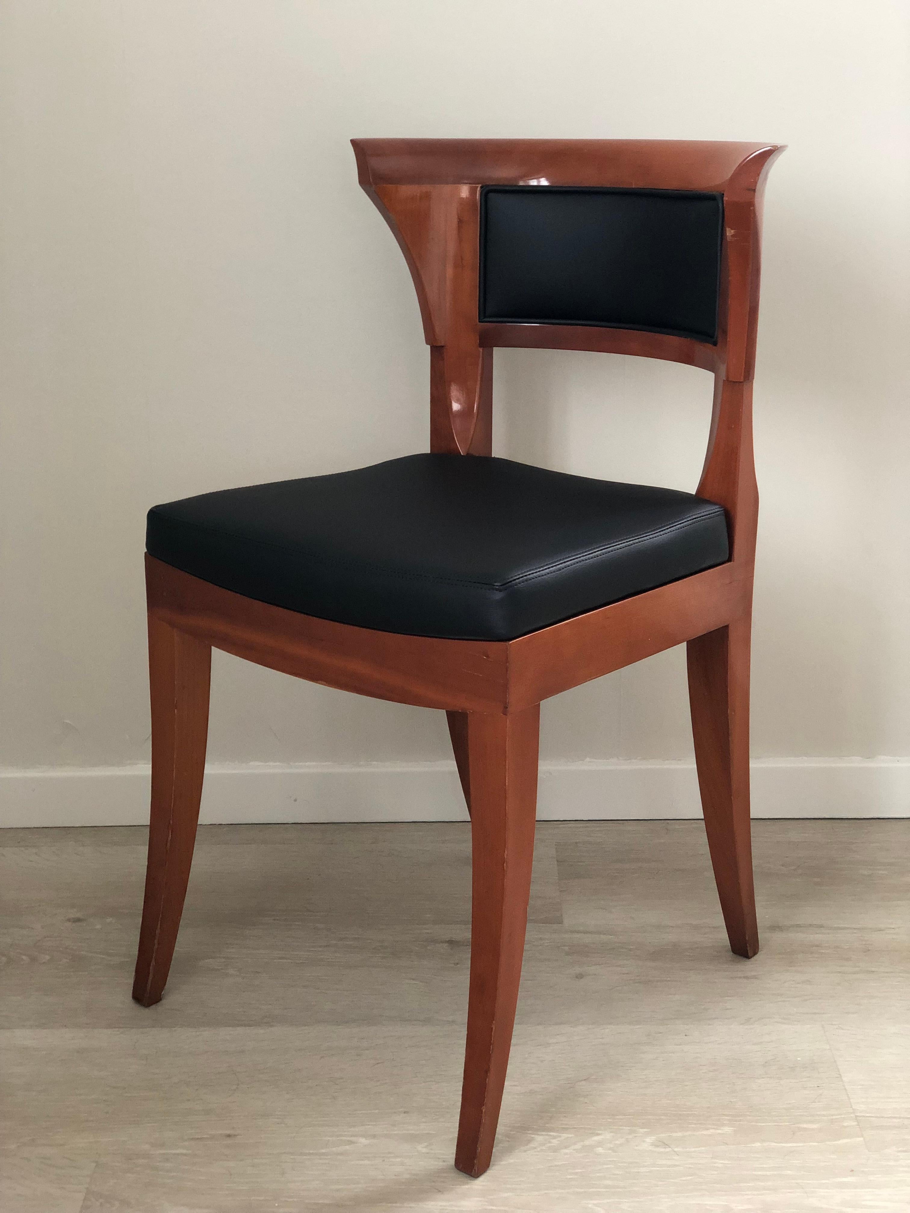 An exquisite design dining chair in solid cherry wood by Leon Krier for Giorgetti. Set of 4. The chair features an elegant curved backrest with high quality black imitation leather on the front, rear and on the seat.
Each chair has its own nameplate