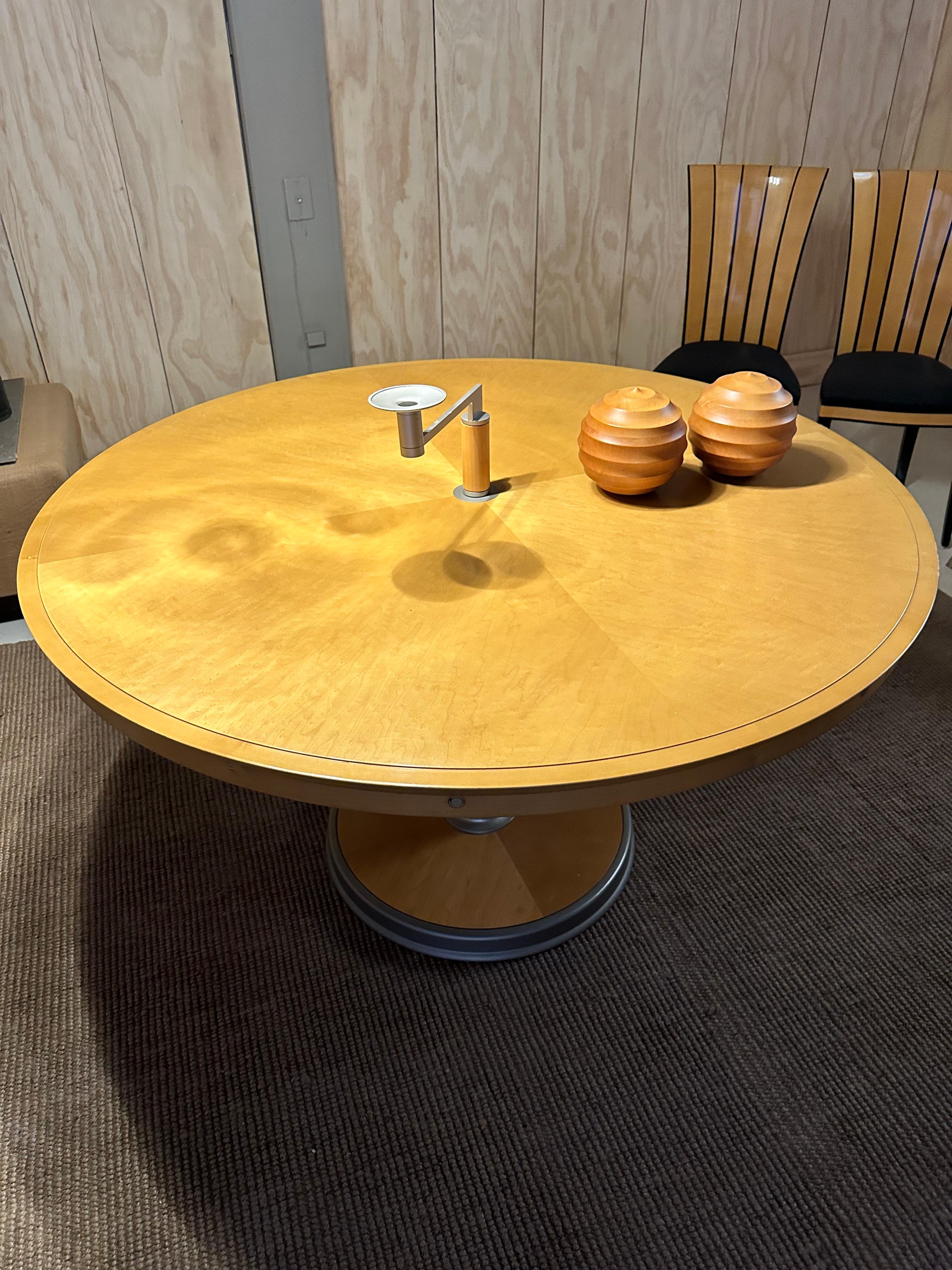 large round maple dining with 4 extensions /retractable supports. quite cleverly designed. heavy weighted base with brush aluminum accent toe kick skirt. wonderful veneer top pattern . exquisite quality manufacturing .
there is a center option for