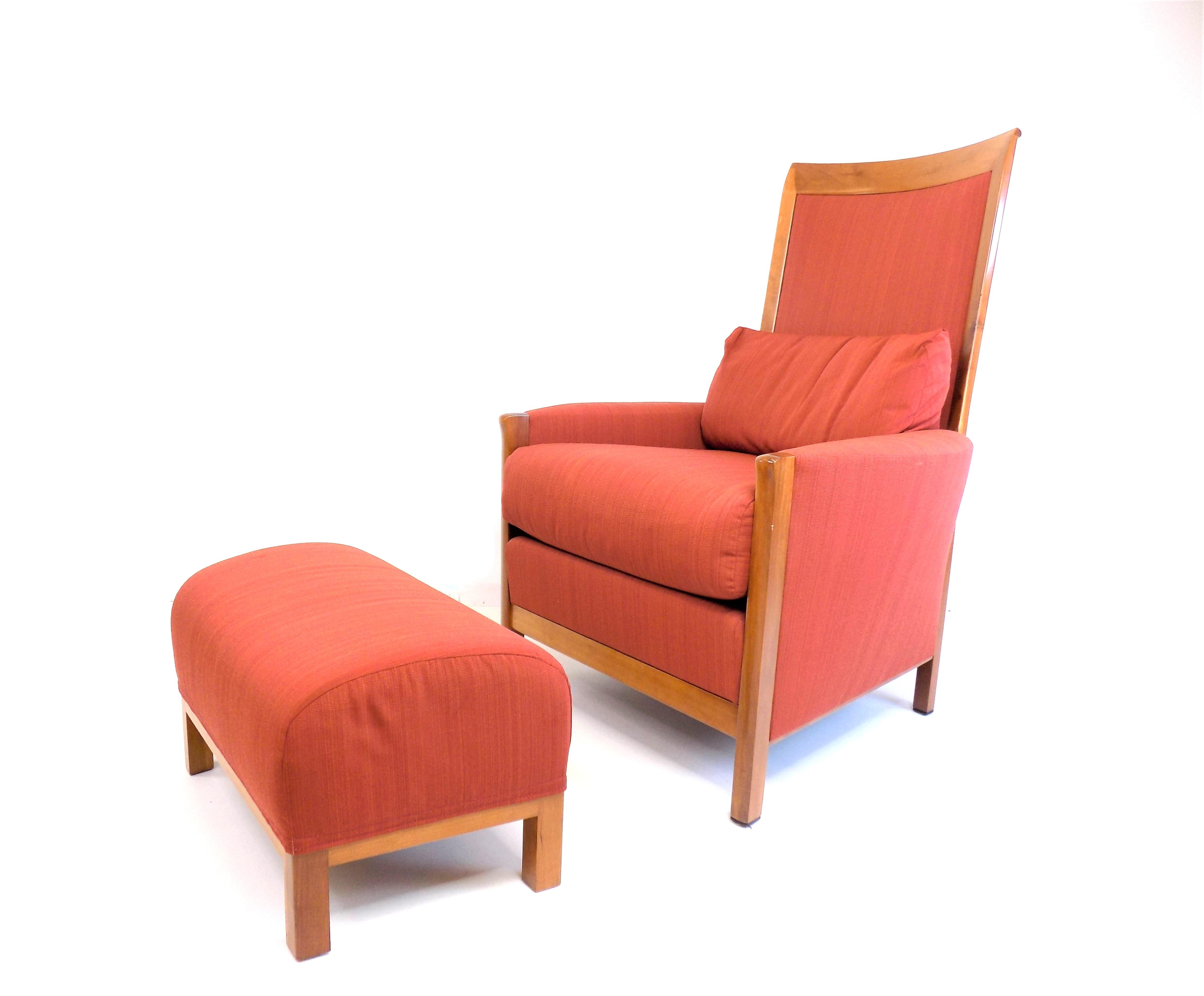 The classic New Gallery armchair was designed by Asnago in the Art Deco style and is in very good condition. The fabric of the armchair and the ottoman are in almost new condition. The wooden elements, made of cherry wood and in a honey-colored