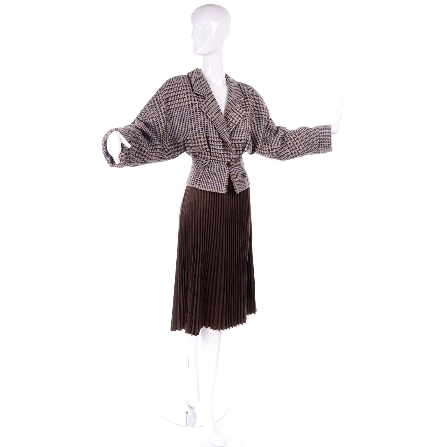 This gorgeous two piece suit was made by Giorgio Armani in the 1980's. The jacket is cropped with oversized dolman sleeves and fitted waist with a gathered pleat on either side. The fabric is in a houndstooth plaid pattern in grey, blue and brown.