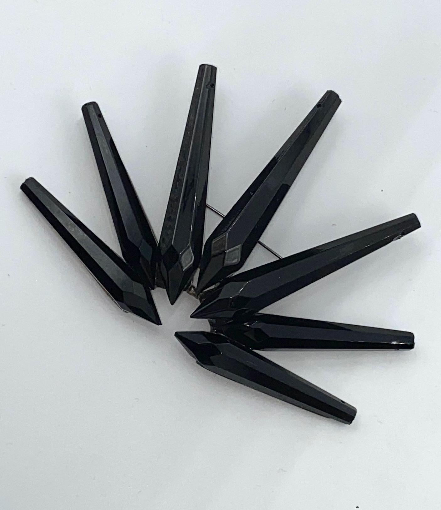 Presented is a large chandelier prism brooch by Giorgio Armani from the 1990s. Seven faceted black glass spikes with drilled tops intended for use on chandeliers are mounted onto a gunmetal grey finish metal setting in a fan formation. The bottom