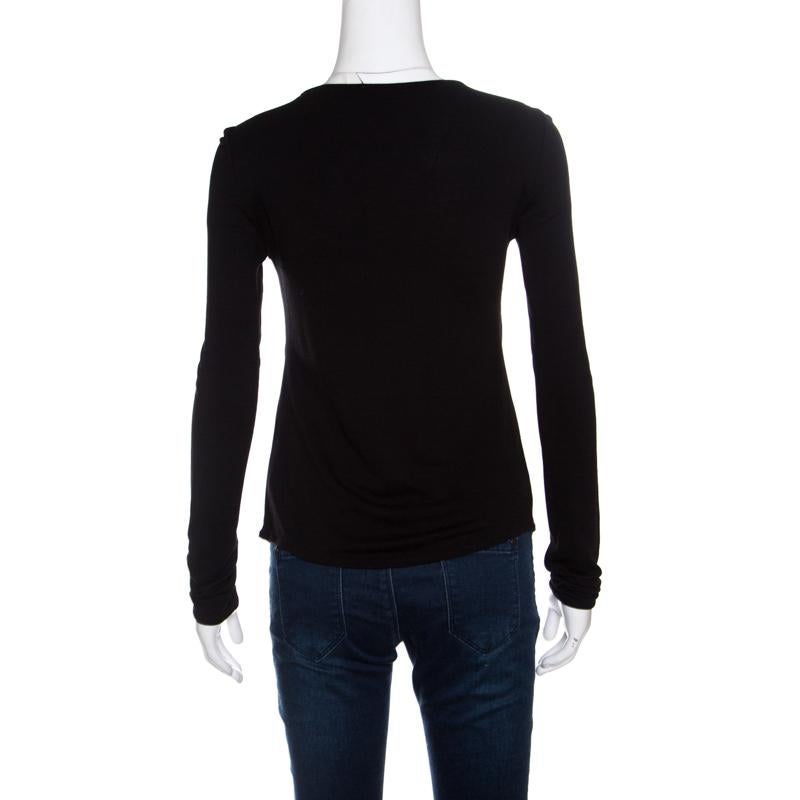 The solid black hue and faux knot detail on the neckline combine to make this Giorgio Armani t-shirt a lovely feminine style that can be flaunted with a lot of variety. It is crafted with blended fabric and features a round neck and long sleeves.