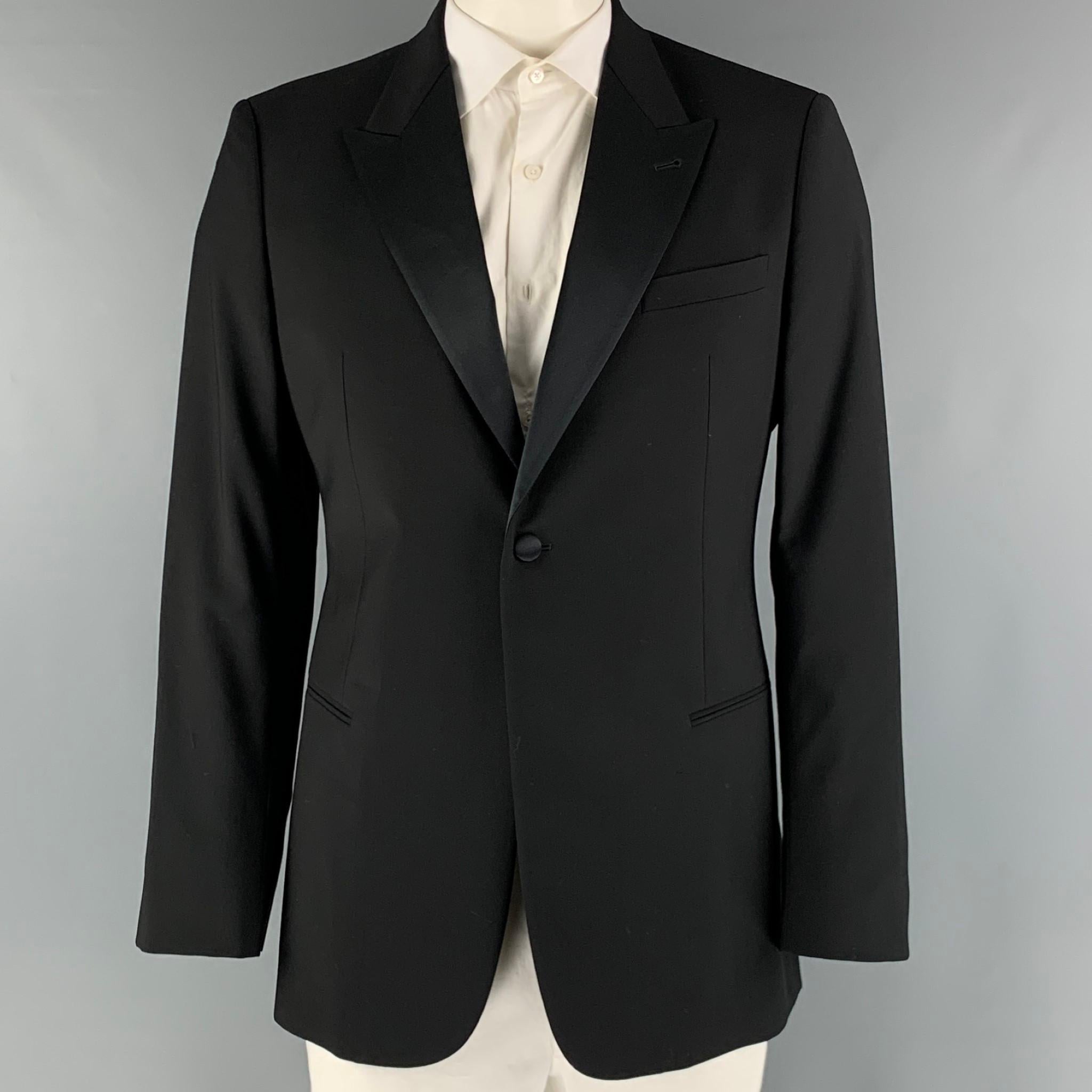 EMPORIO ARMANI tuxedo sport coat comes in a black wool woven material with a full liner featuring a peak lapel, welt pockets, and a single button closure. Made in Italy.

Excellent Pre-Owned Condition.
Marked: 52

Measurements:

Shoulder: 18.5