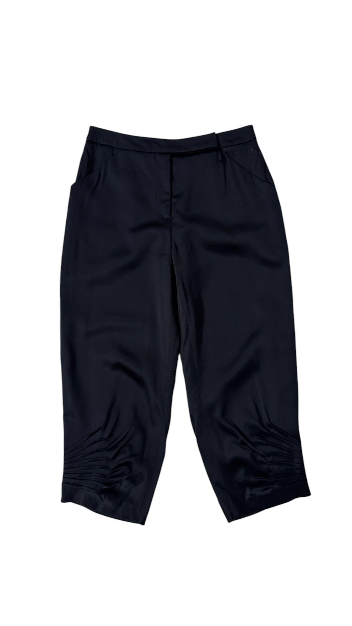 Este pantalón recortado, ejemplo de la refinada sastrería de Giorgio Armani de principios de la década de 2000, pertenece a la colección Ready-to-Wear Otoño 2002. Confeccionados en satén azul noche, presentan una silueta fluida que llega justo por