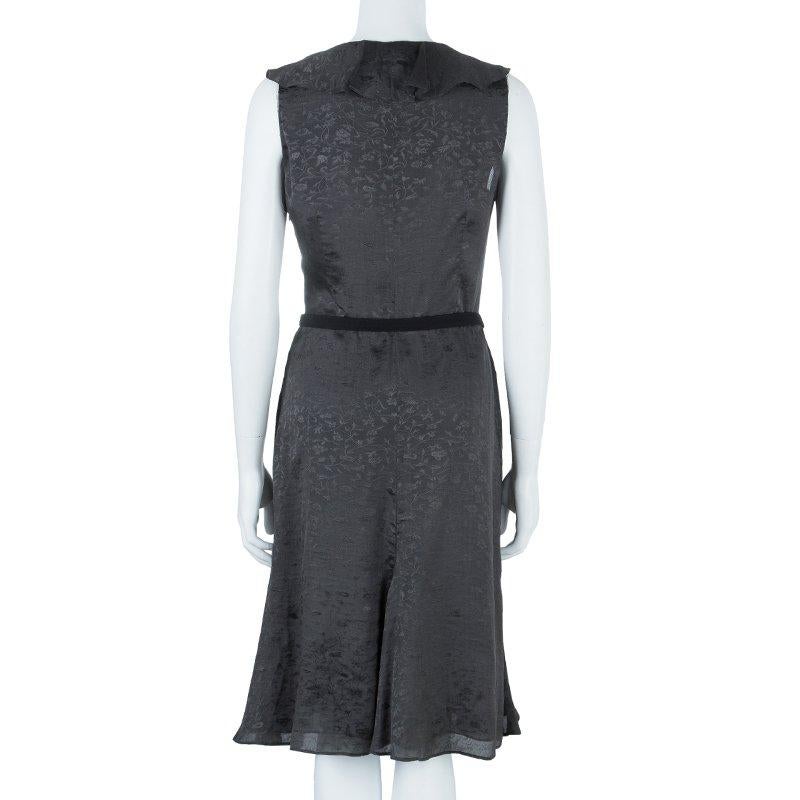 The iconic Giorgio Armani label is known for its sophisticated and impeccably crafted pieces. This elegant textured dress is crafted in grey silk. With a flair skirt and sleeveless cut, it features a feminine silhouette enhanced with a belted waist