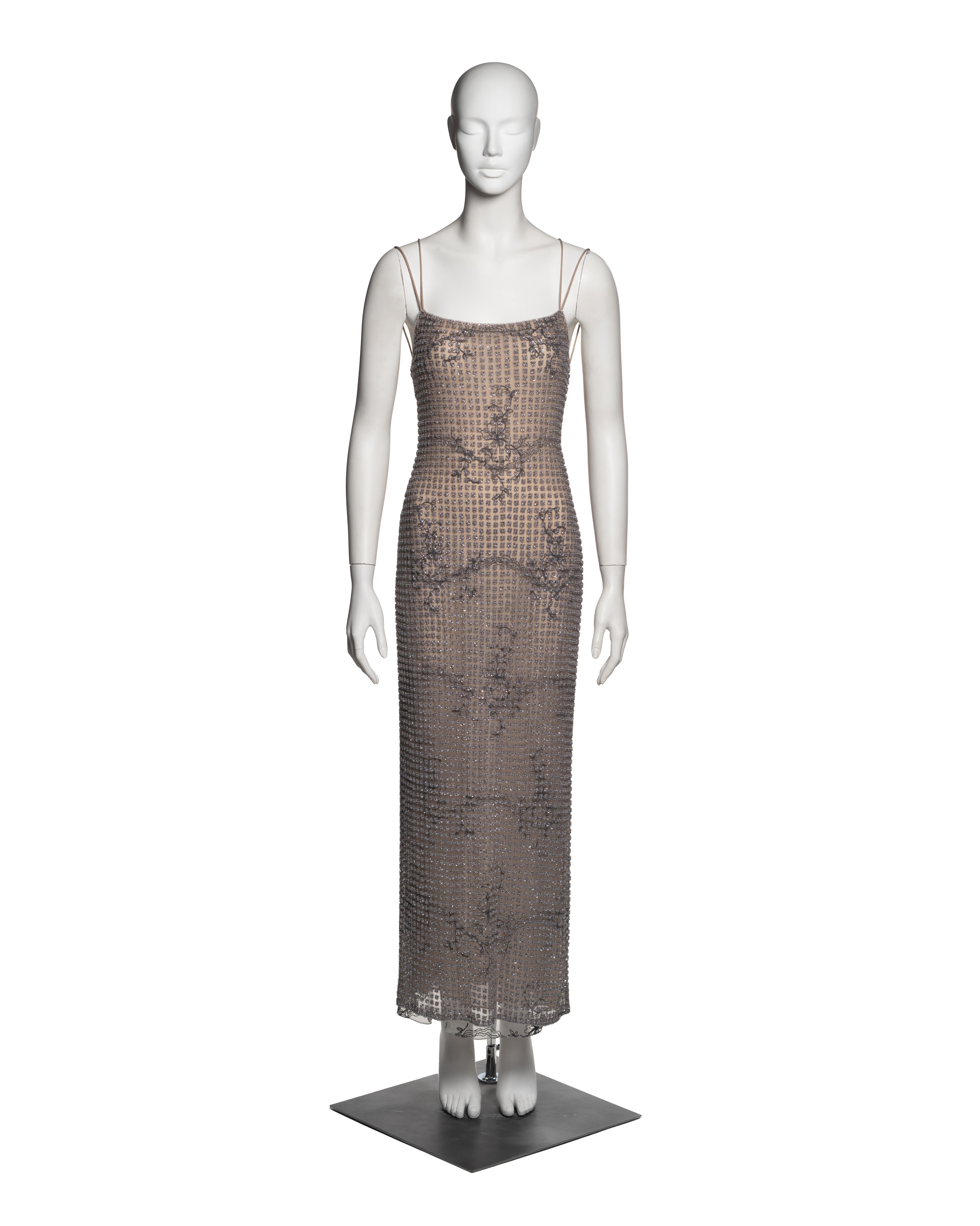 This Giorgio Armani evening dress from the Spring-Summer 2000 collection exemplifies the designer’s signature balance of understated minimalism and opulent detailing. The dress features a nude silk slip underlay intricately embroidered with floral