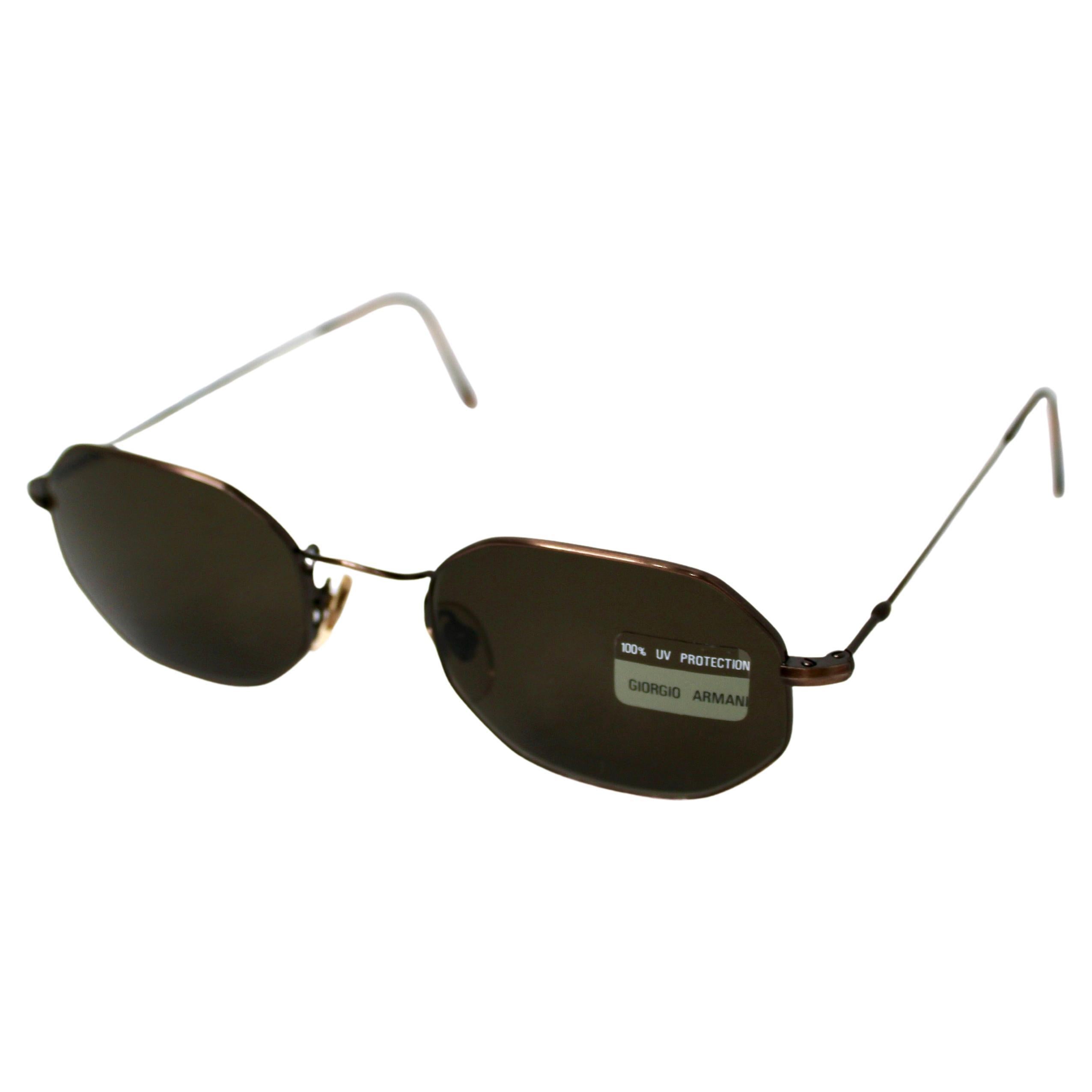Ces lunettes de soleil Giorgio Armani à monture octogonale en métal, datant des années 1990, exsudent une sophistication intemporelle et un attrait vintage. Fabriquées avec une monture en métal cuivré, elles présentent une forme octogonale