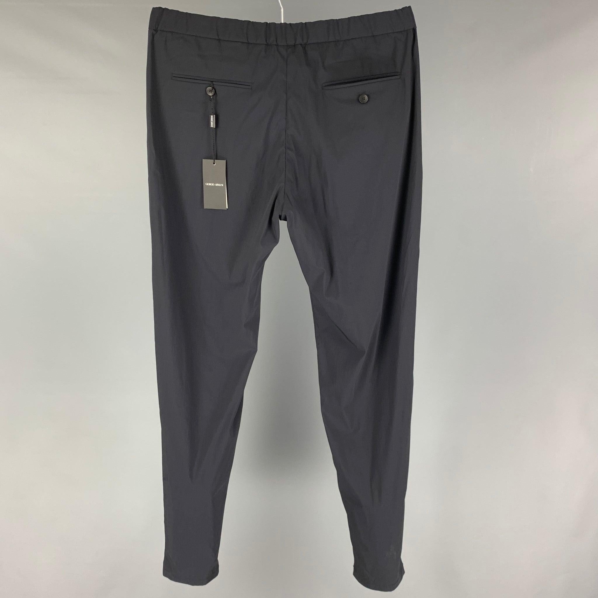 GIORGIO ARMANI dress pants comes in a navy wool blend featuring a slim fit, elastic waistband, front tab, and a zip fly closure. Made in Italy.
New with tags. 

Marked:   50 

Measurements: 
  Waist: 34 inches Rise: 11 inches Inseam: 36 inches Leg