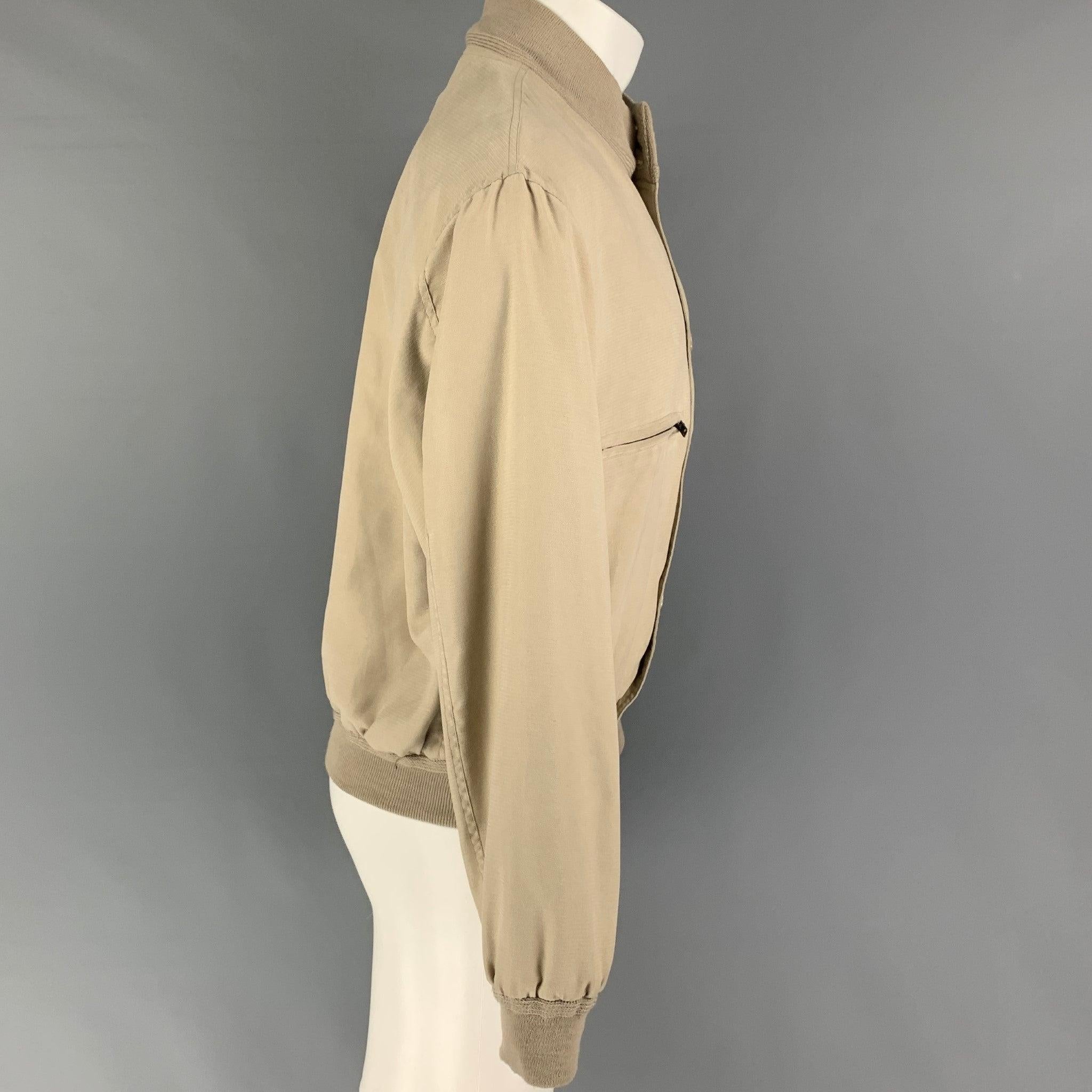 GIORGIO ARMANI jacket comes in a beige polyester featuring a bomber style, ribbed hem, zipper pockets, and a buttoned closure. Made in Italy.
Good
Pre-Owned Condition. Moderate discoloration throughout.  

Marked:   38 

Measurements: 
 
Shoulder: