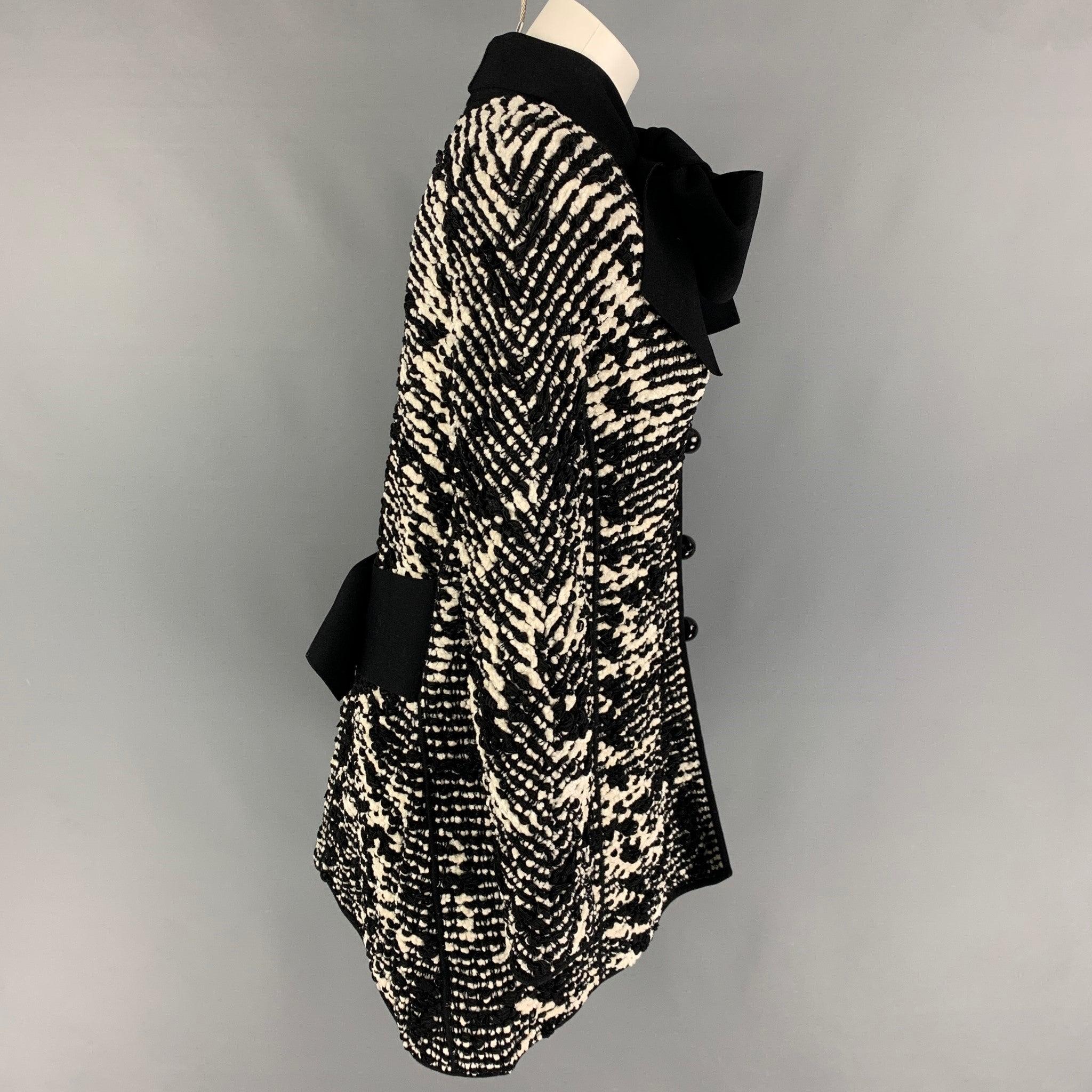 Cappotto di Giorgio Armani in misto viscosa intrecciata bianca e nera, caratterizzato da un ampio cinturino e da una chiusura con bottoni. Le cinghie possono essere accostate in altri modi. Prodotto in Italia.
Eccellente condizione di usato.