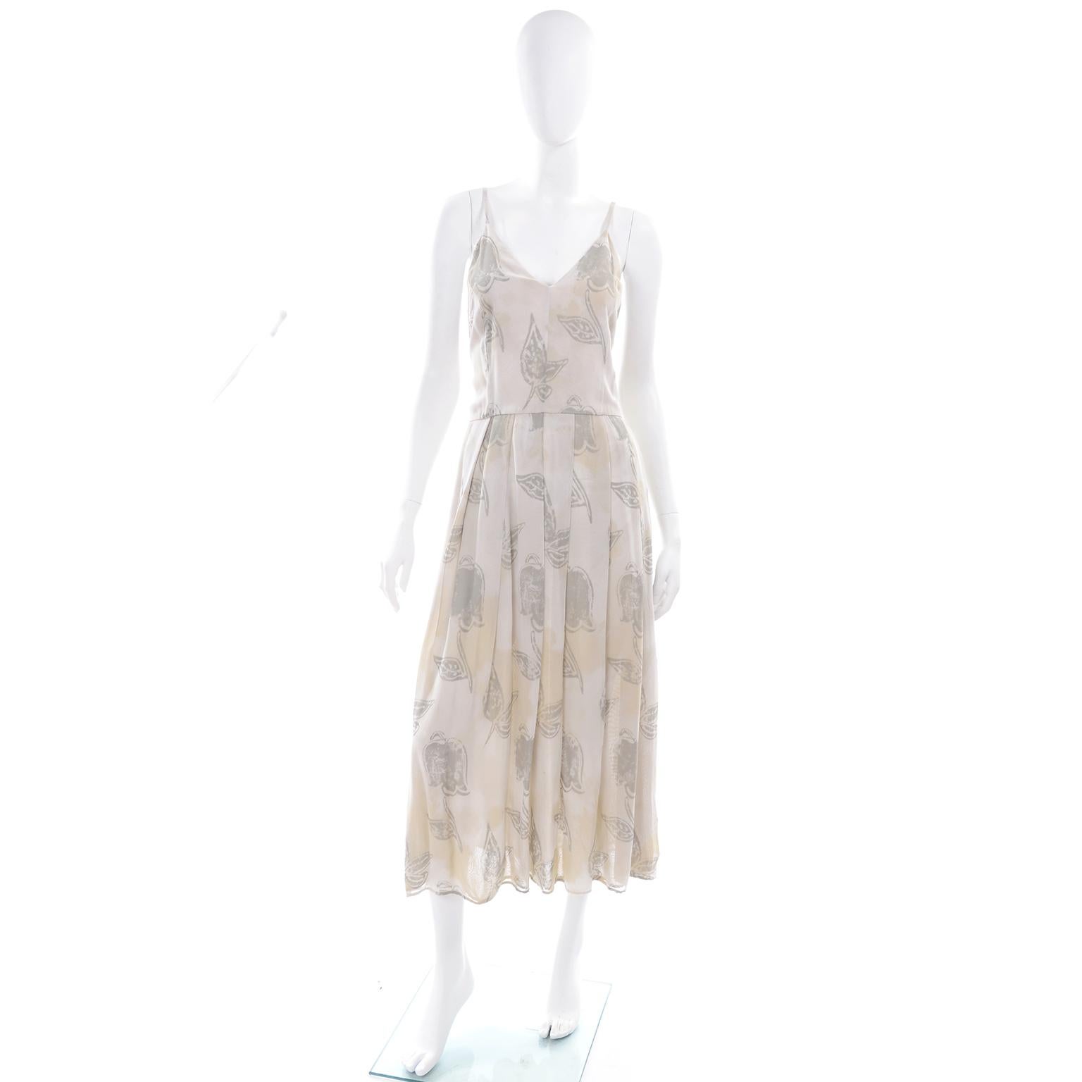 This is a unique vintage Giorgio Armani pale khaki cream and sage green dress in a pattern that has abstract leaves and purposeful color layover that almost looks like tea staining. This dress has a V-neck in front and a V in back, a pleated skirt,