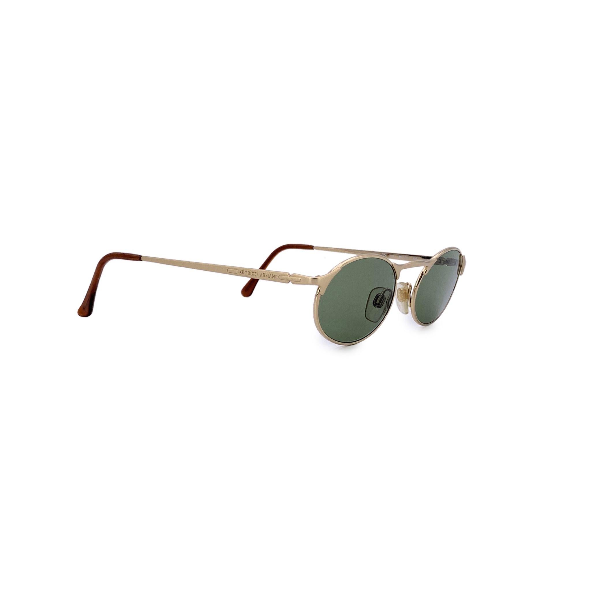Diese Vintage-Sonnenbrille von Giorgio Armani, Modell 224 col. 773 - 48/20 140mm, ist ein seltener und auffälliger Fund aus der experimentellen Ära des Designers. Der ovale Rahmen aus goldfarbenem Metall verleiht dem Rahmen einen modernen,