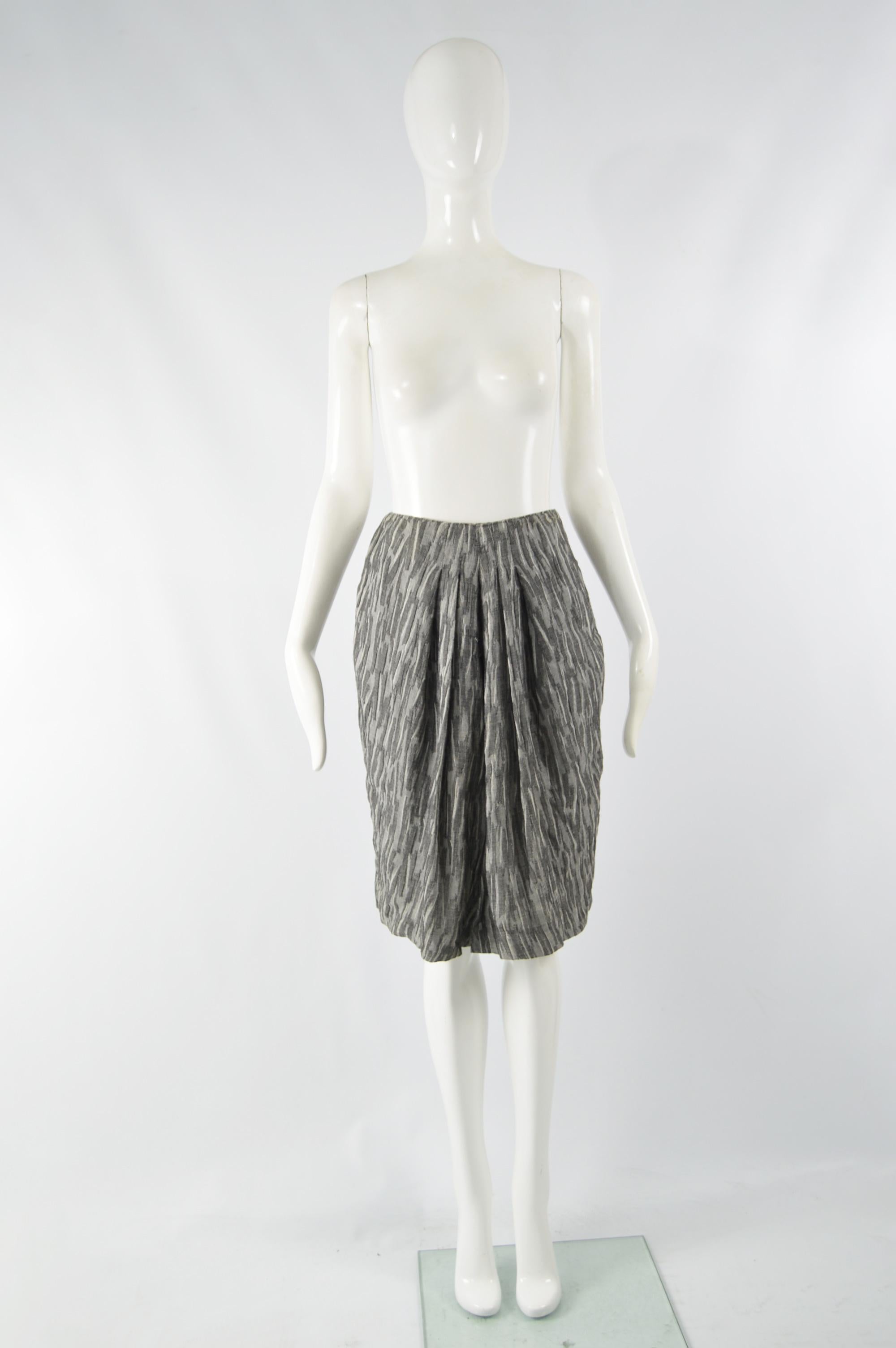 A chic vintage womens soft pleated skirt from the 90s by iconic fashion designer, Giorgio Armani for his mainline label. In a grey wool gauze fabric with a high split that creates draping / soft pleats at the front. 

Size: Marked vintage IT 42 but