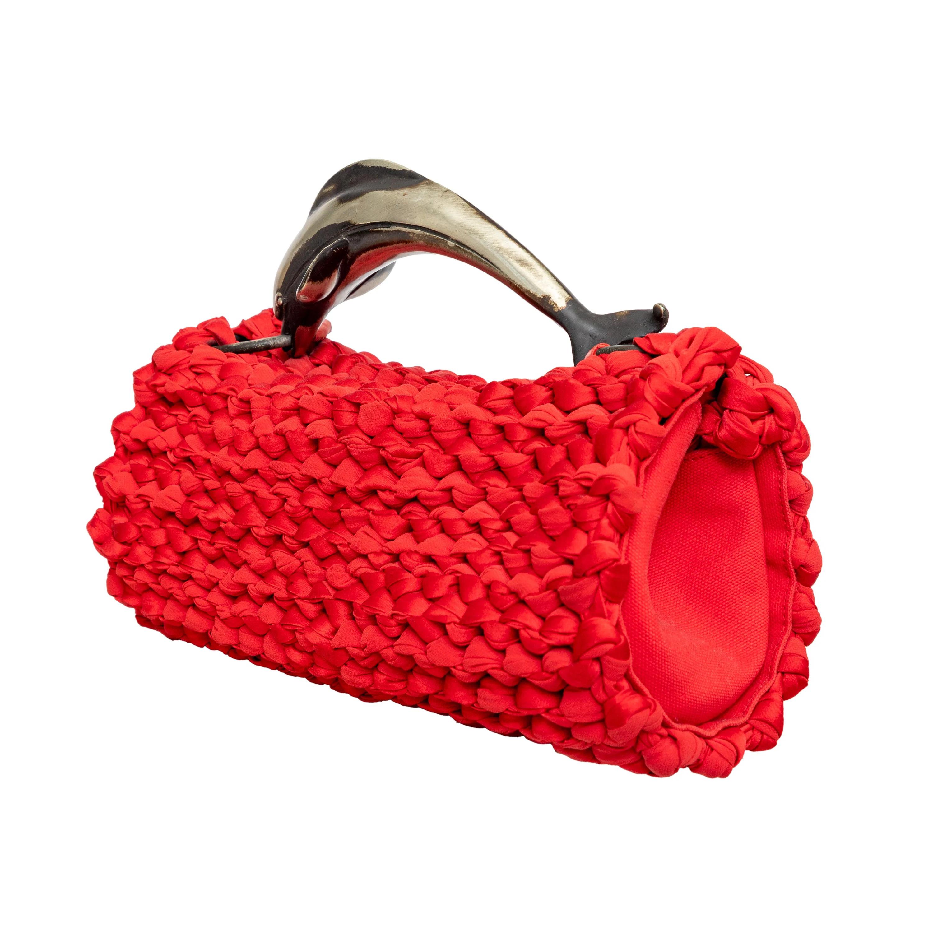 Add a touch of vintage charm to your outfit with the Giorgrio Armani Fabric Crotchet Handbag. Its unique metal dolphin handle and bright red fabric crochet design make it a statement piece. The snap closure and interior flap pocket add convenience