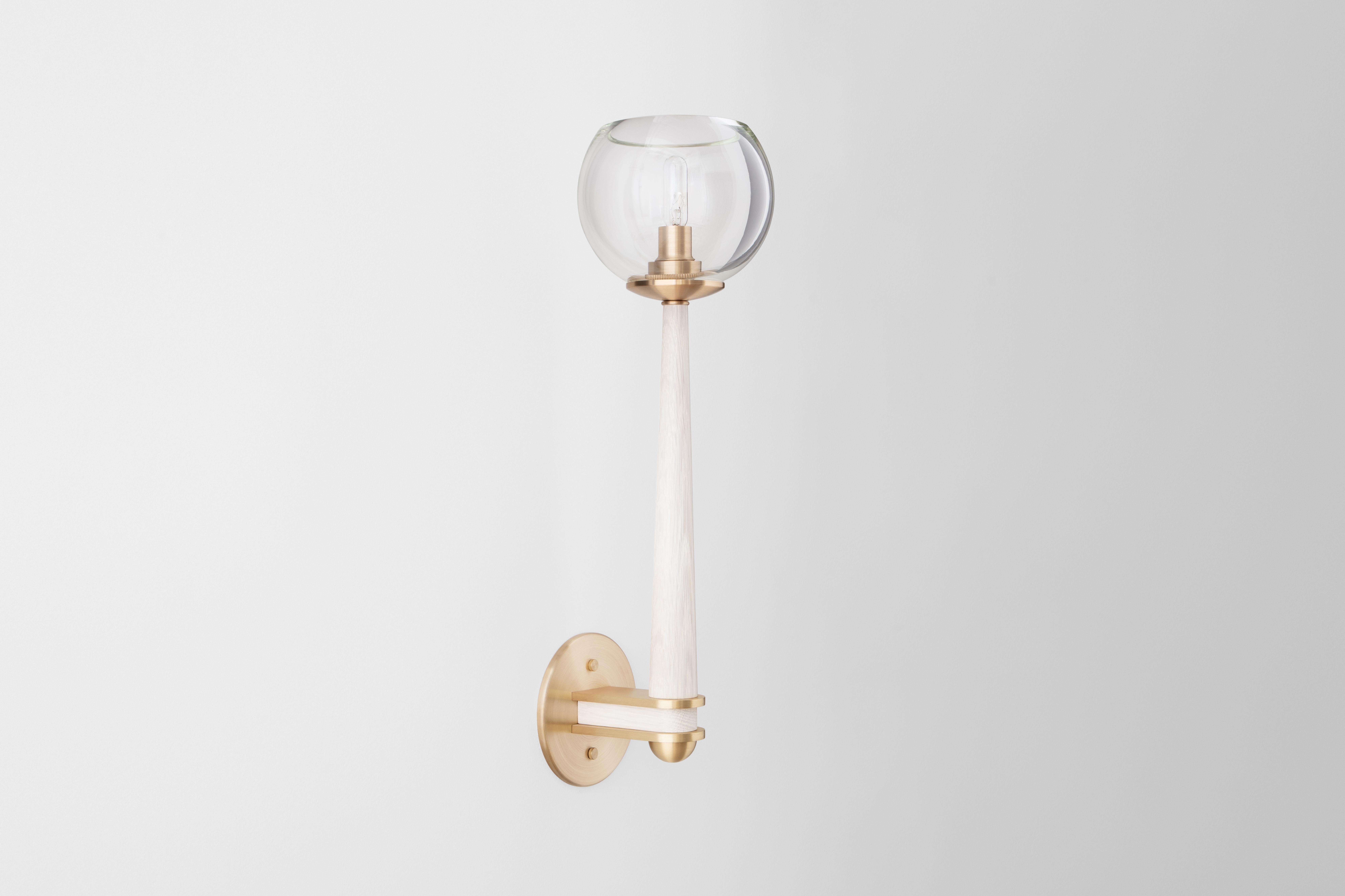 The Giotto sconce unifies three luxe materials. A hand blown globe rests upon a tapered wooden body. Precisely machined brass elements add ornament and strength. Wood, glass and brass finishes can be customized to coordinate with many architectural