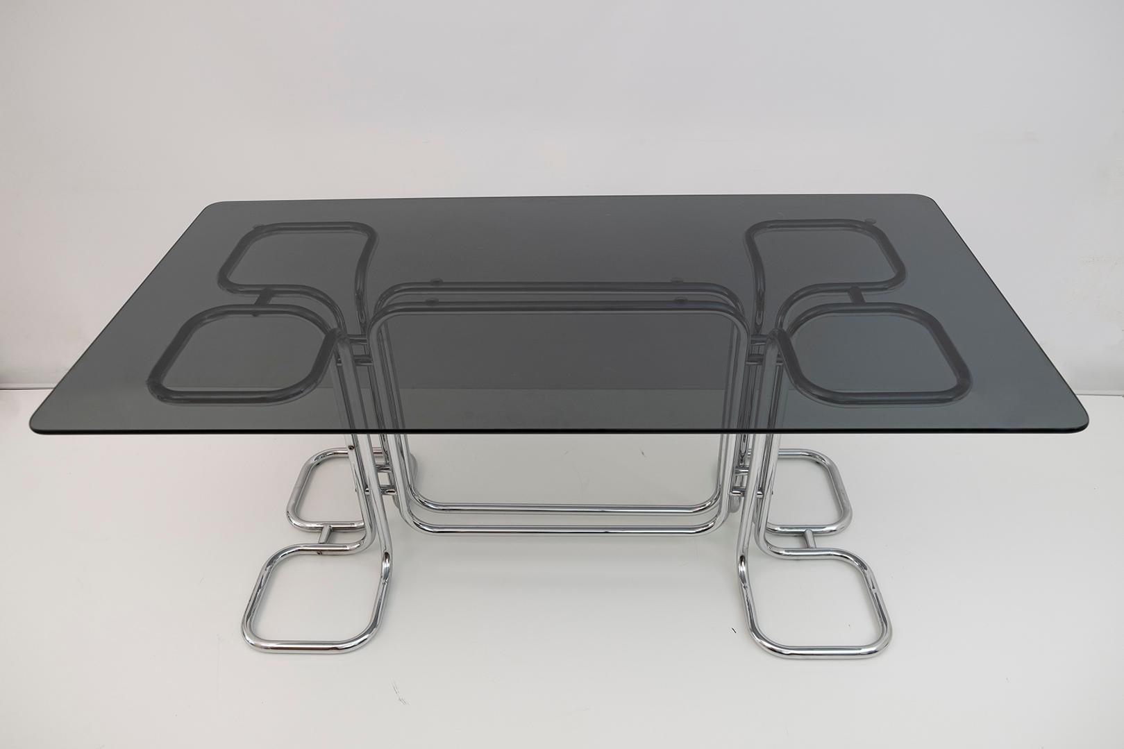 Rectangular dining table with mid-century chrome base and smoked glass top. This wonderful dining table was designed by Giotto Stoppino in Italy in the 1970s.

This extraordinary piece is unique in that its complex lines are built by merging only