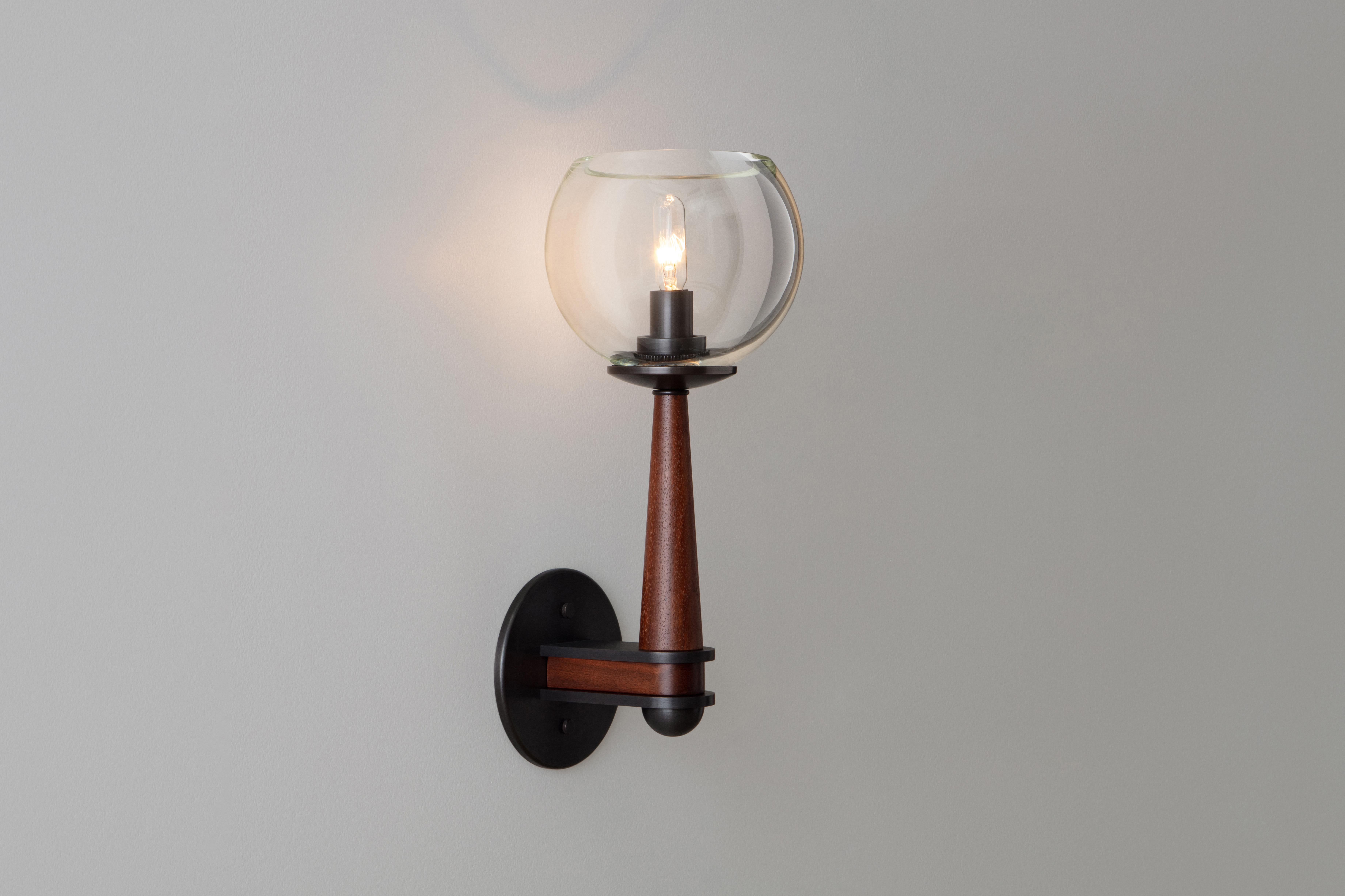 The Giotto Sconce unifies three luxe materials. A hand-blown globe rests upon a tapered wooden body. Precisely machined brass elements add ornament and strength. Wood, glass and brass finishes can be customized to coordinate with many architectural