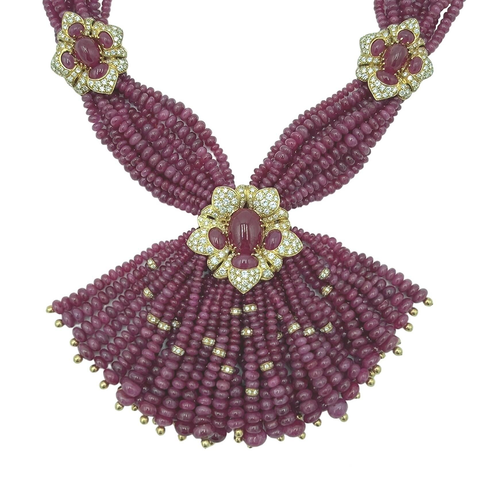 Halskette aus 18 Karat Gelbgold, Rubin und Diamanten, Giovane, Italien, um 1990.  Zehn Stränge aus abgestuften Rubinperlen, die von zwei floralen Motiven zusammengehalten werden, in deren Mitte sich jeweils ein ovaler Rubin-Cabochon befindet und die