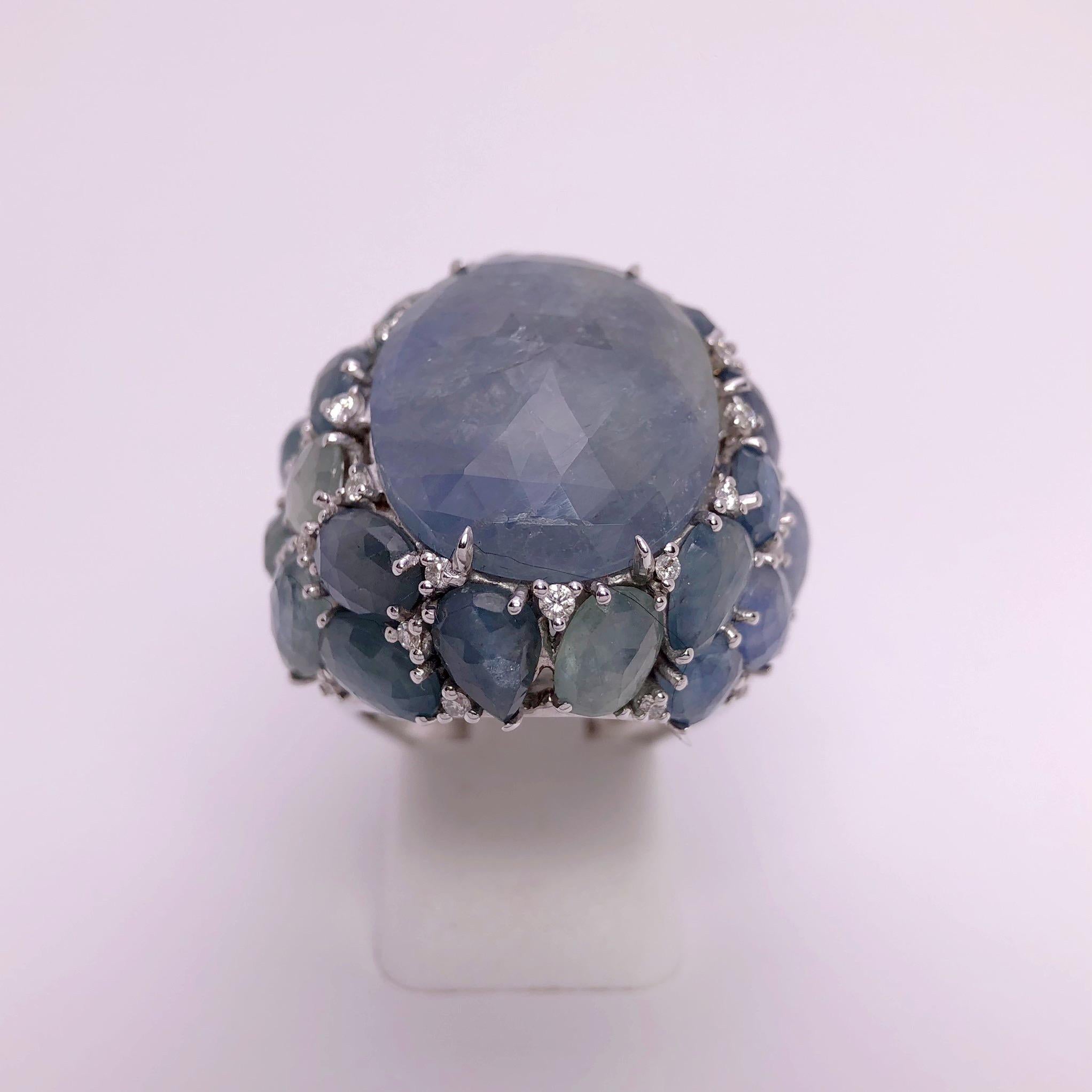 Created by Giovanni Ferraris of Italy , this Sapphire ring is a work of art. The center light blue oval opaque sapphire is a briolette faceted cabachon that measures 21.5mm x 17mm. . The ring has a spectacular setting designed with icy blue and blue