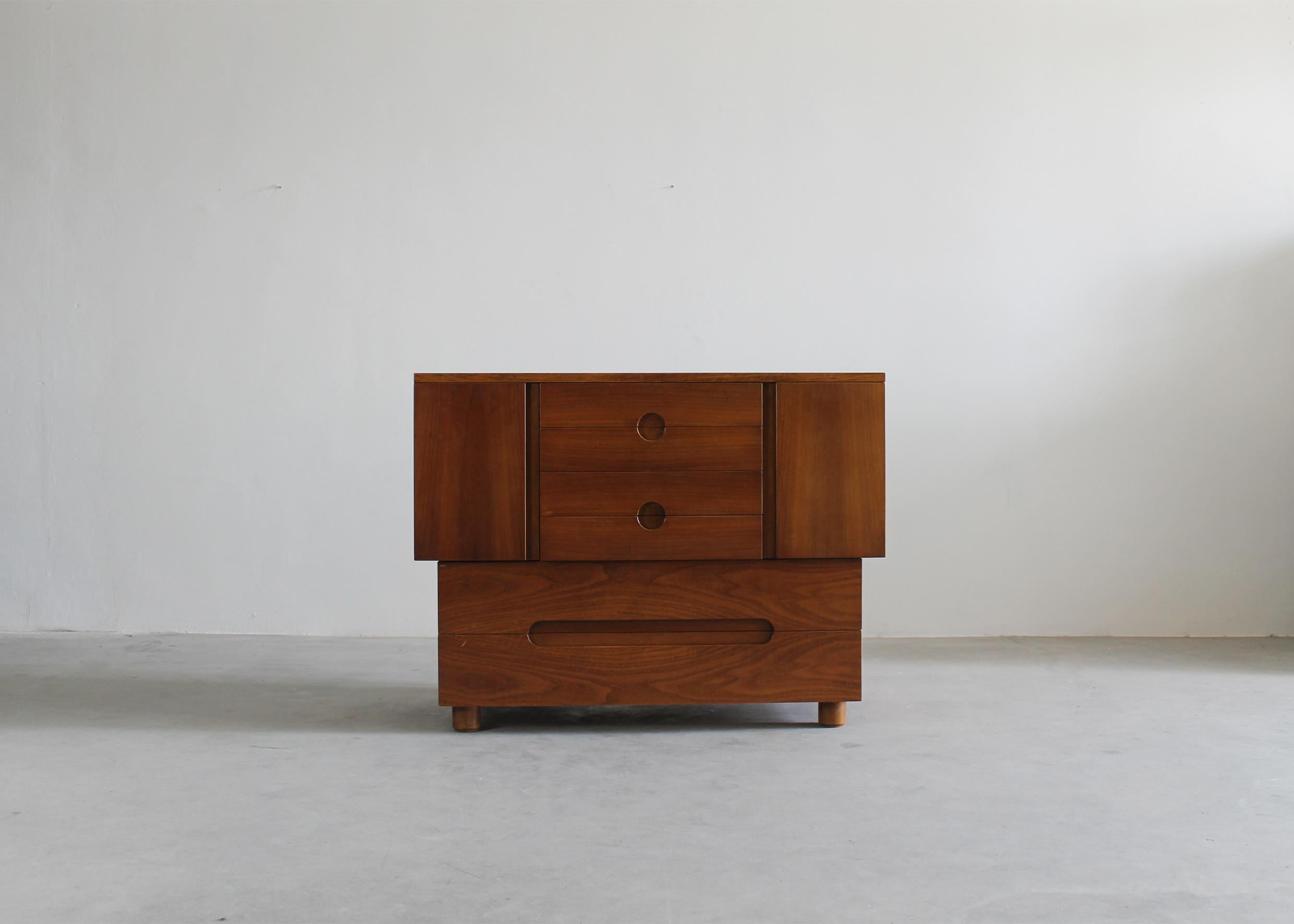 Cassettiera Serena realizzata interamente in legno di noce, con due ante frontali e sei cassetti (quattro più piccoli sul lato alto e due più grandi sul lato inferiore).

Disegnata da Giovanni Michelucci per Poltronova, 1955, Italia. 

Firma incisa