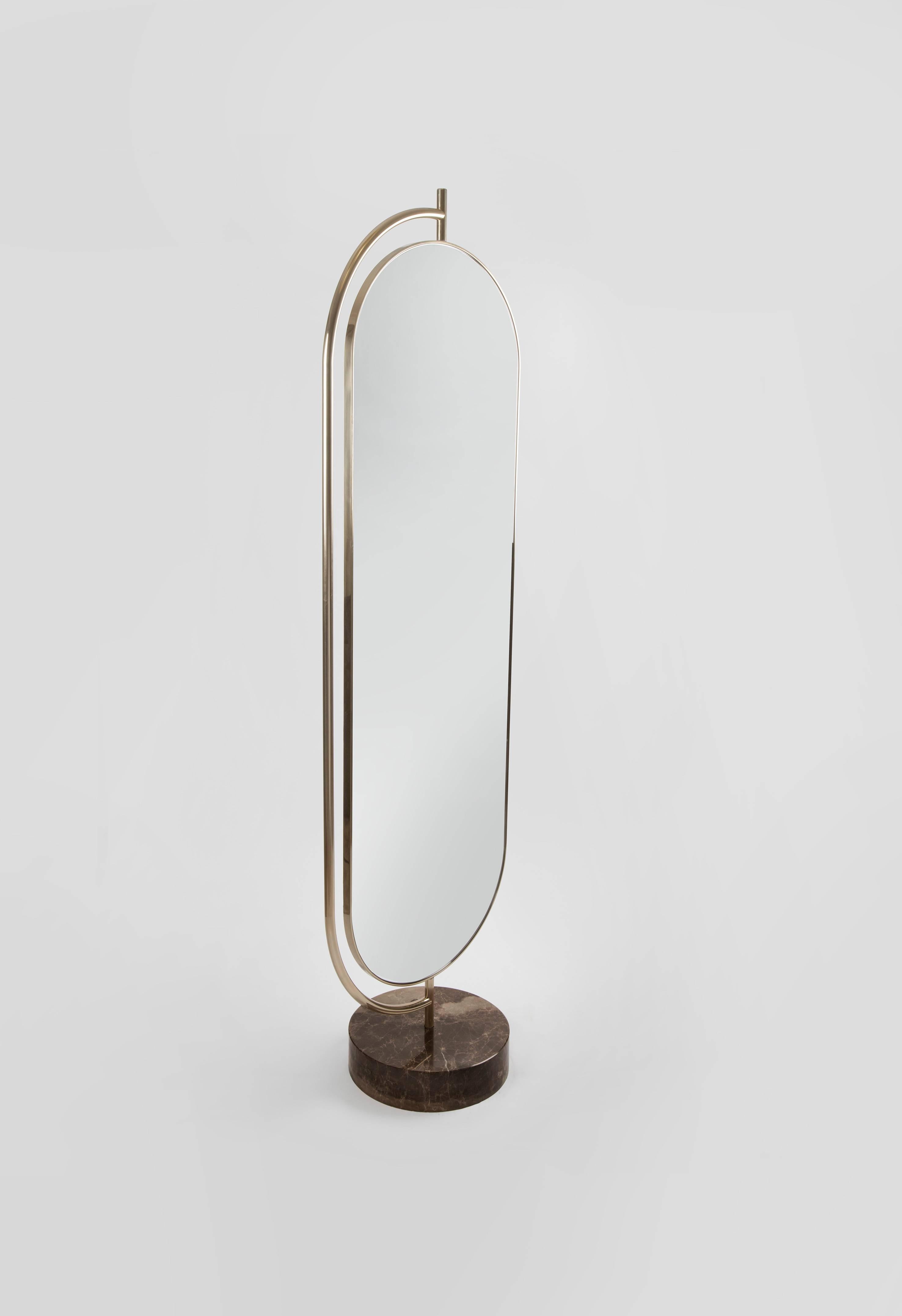 Giove is a full length mirror supported by a polished marble base with a champagne brass structure. The back of the mirror is upholstered in velvet. Giove can rotate inside the brass structure, offering new shapes and angles every time it is