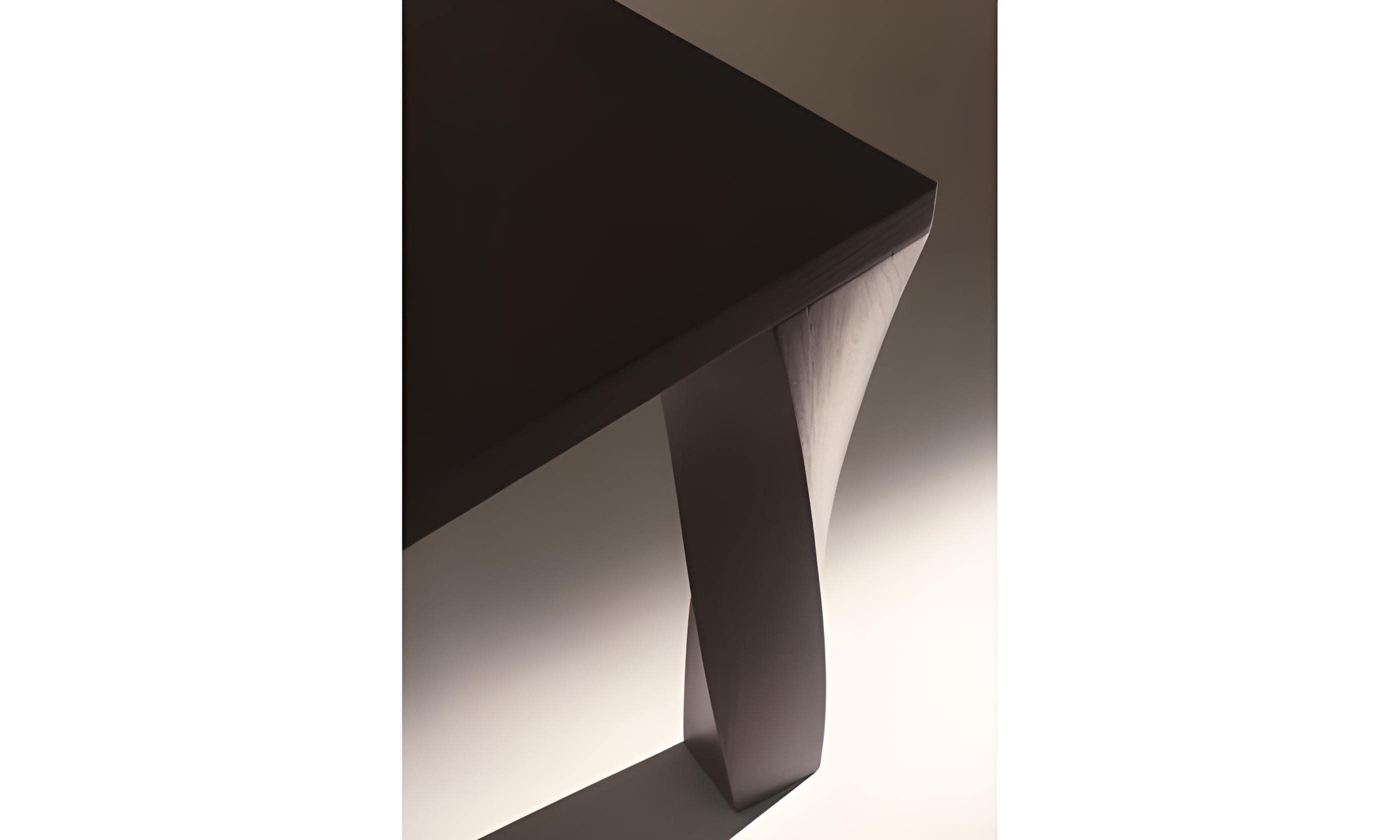 Gira che ti rigira is a rectangular dining table, crafted from solid elm wood stained in matt black. This exceptional piece showcases gracefully twisted legs, adding a touch of whimsy and artistry to its design, while also ensuring stability and