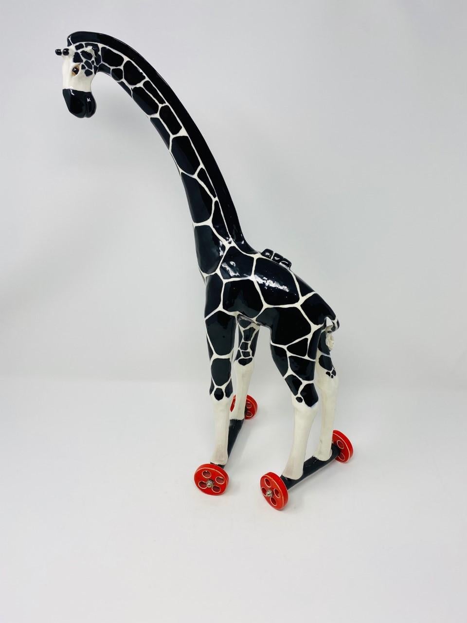Beautiful and commanding ceramic sculpture. This piece is whimsical as it is enchanting. The giraffe form is sculpted beautifully and balances over wheels that move smoothly. A secret compartment is constructed within the body of the giraffe with a