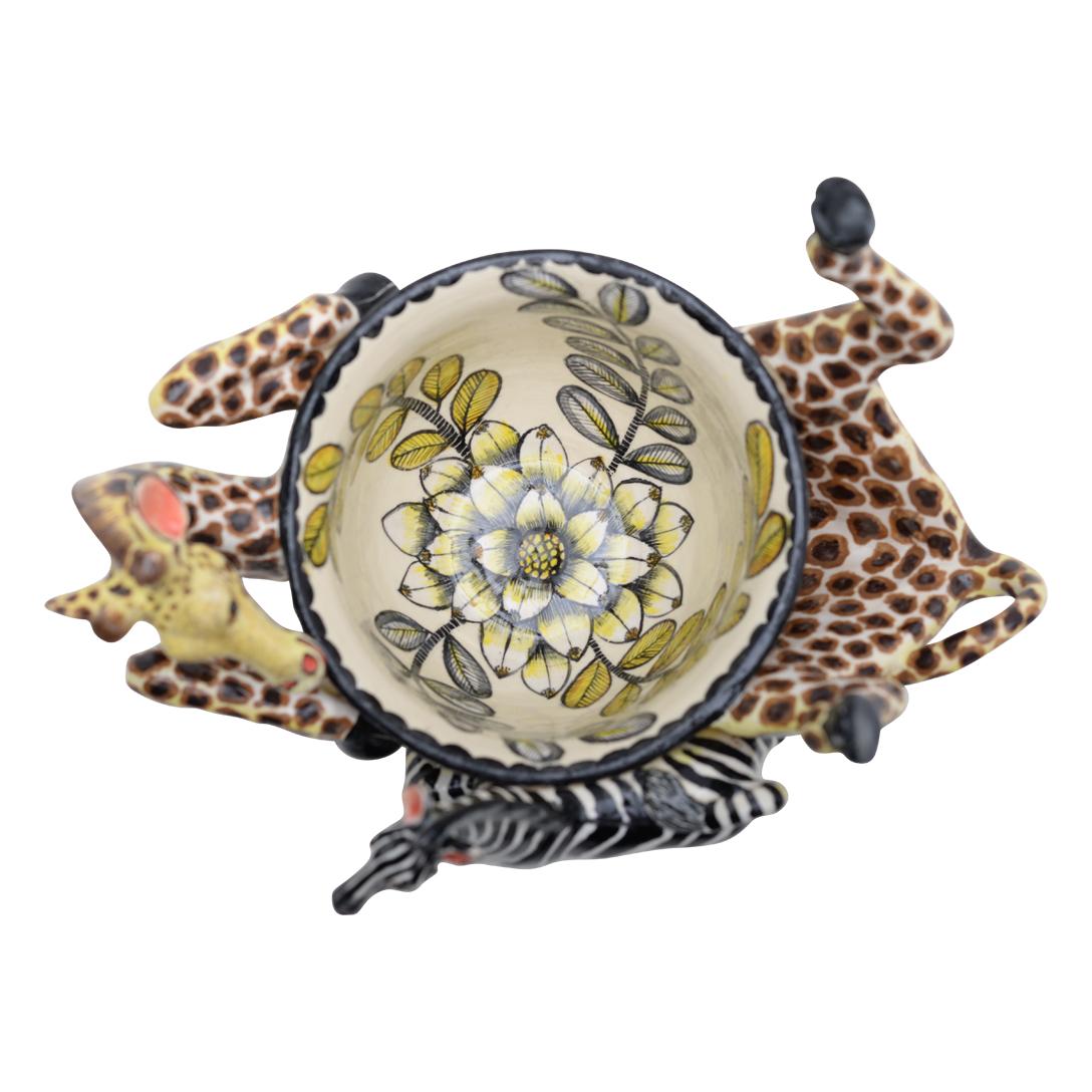 This Giraffe Peanut Bowl was hand sculpted by the renowned artisan Sondelani Ntshalintshali and beautifully painted by Zinhle Nene both from South Africa. This exquisite ceramic creation stands 6 inches high, measuring 8 inches in length and 5