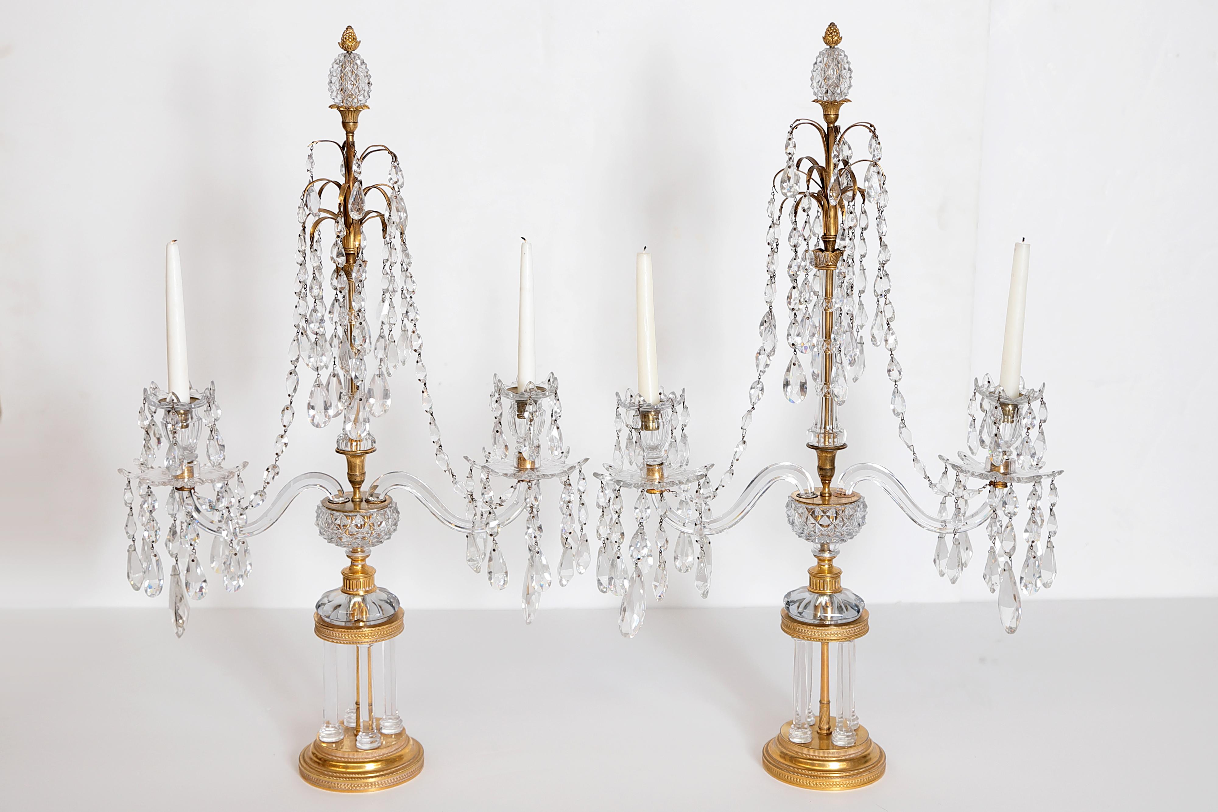 A beautiful pair of period English Regency candleabra / girandoles of cut-glass and gilt bronze, base of four glass columns, columnar body with two cut-glass branches (arms) fitted with cut-glass drip pans dripping and swagged with cut-glass pear