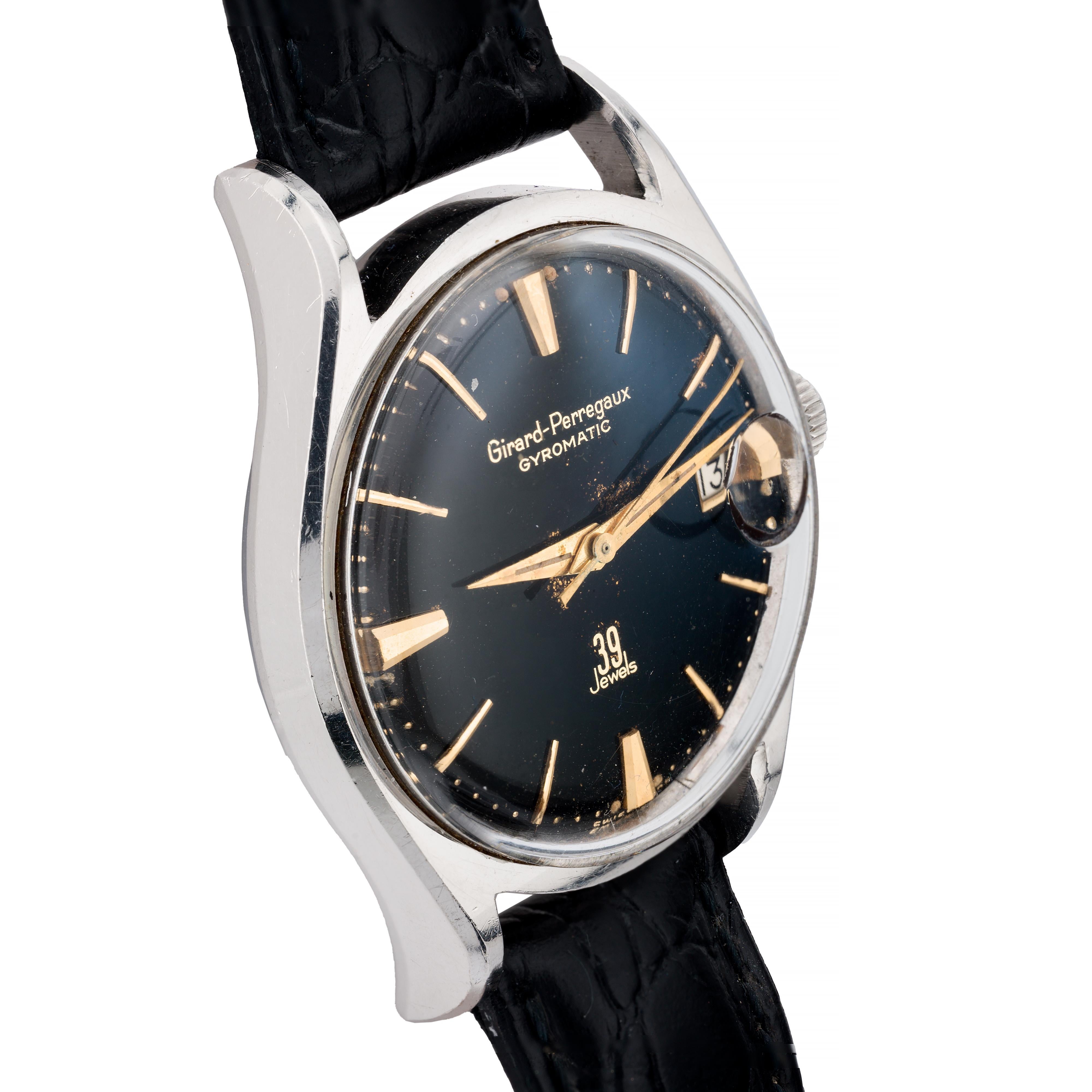 Aston Estate Jewelry stellt vor:

Eine Gyromatic-Armbanduhr von Girard Perregaux aus rostfreiem Stahl.

Das runde Gehäuse misst 35 mm in der Breite und hat ein schwarzes, vergoldetes Zifferblatt mit Stabindexen. Das Zifferblatt enthält ein