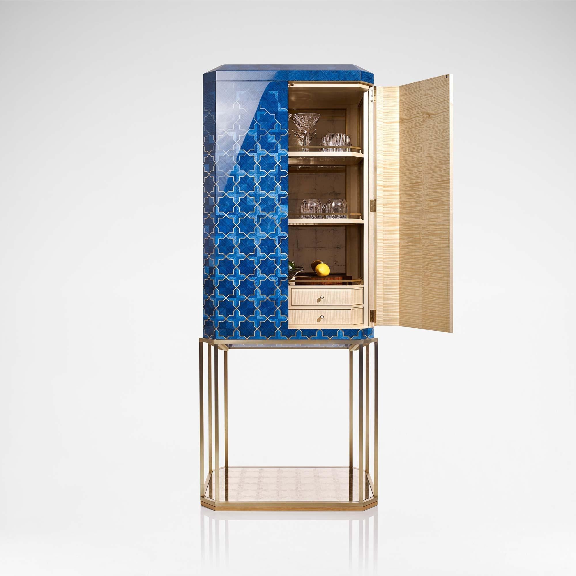 The Girih cabinet explores Islamic pattern through detailed wooden marquetry in brilliant sapphire blue and rich gold tones. The chest is cradled by a metal base crafted with a brushed brass finish with a glass eglomisé panel at the base.

At the